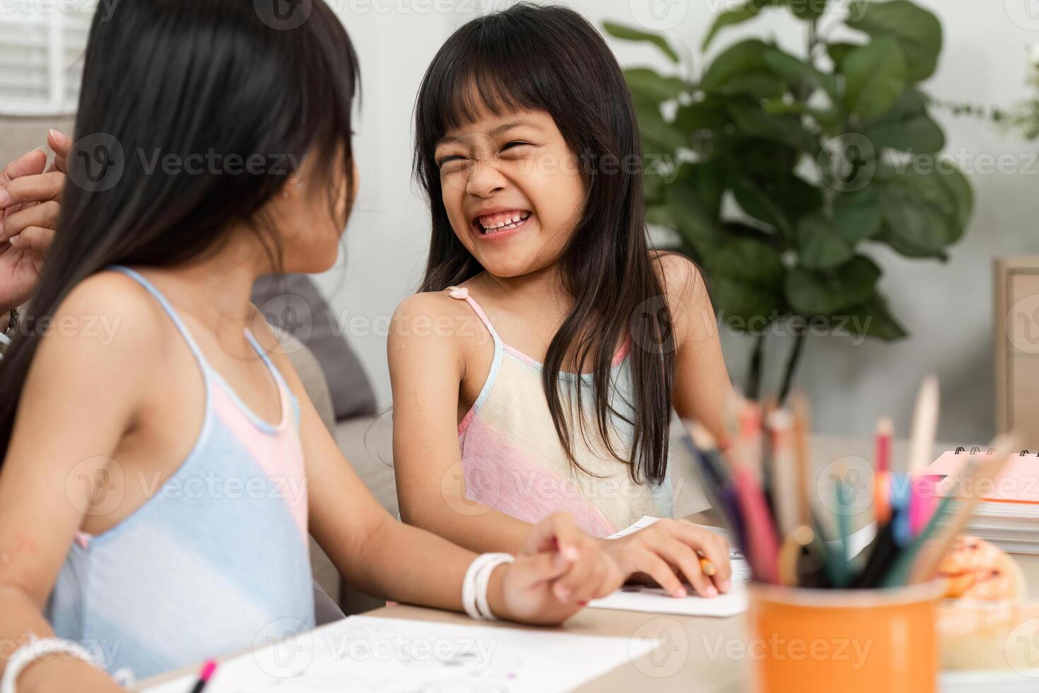 Sisterhood and Creativity. Two young girls sharing laughter while drawing together. photo