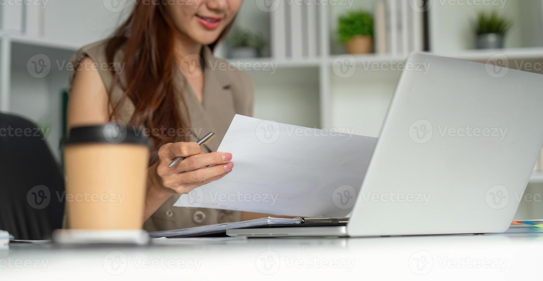 Business Analysis and Engagement. A woman engaged in her work, analyzing documents with a focused expression at her desk. photo