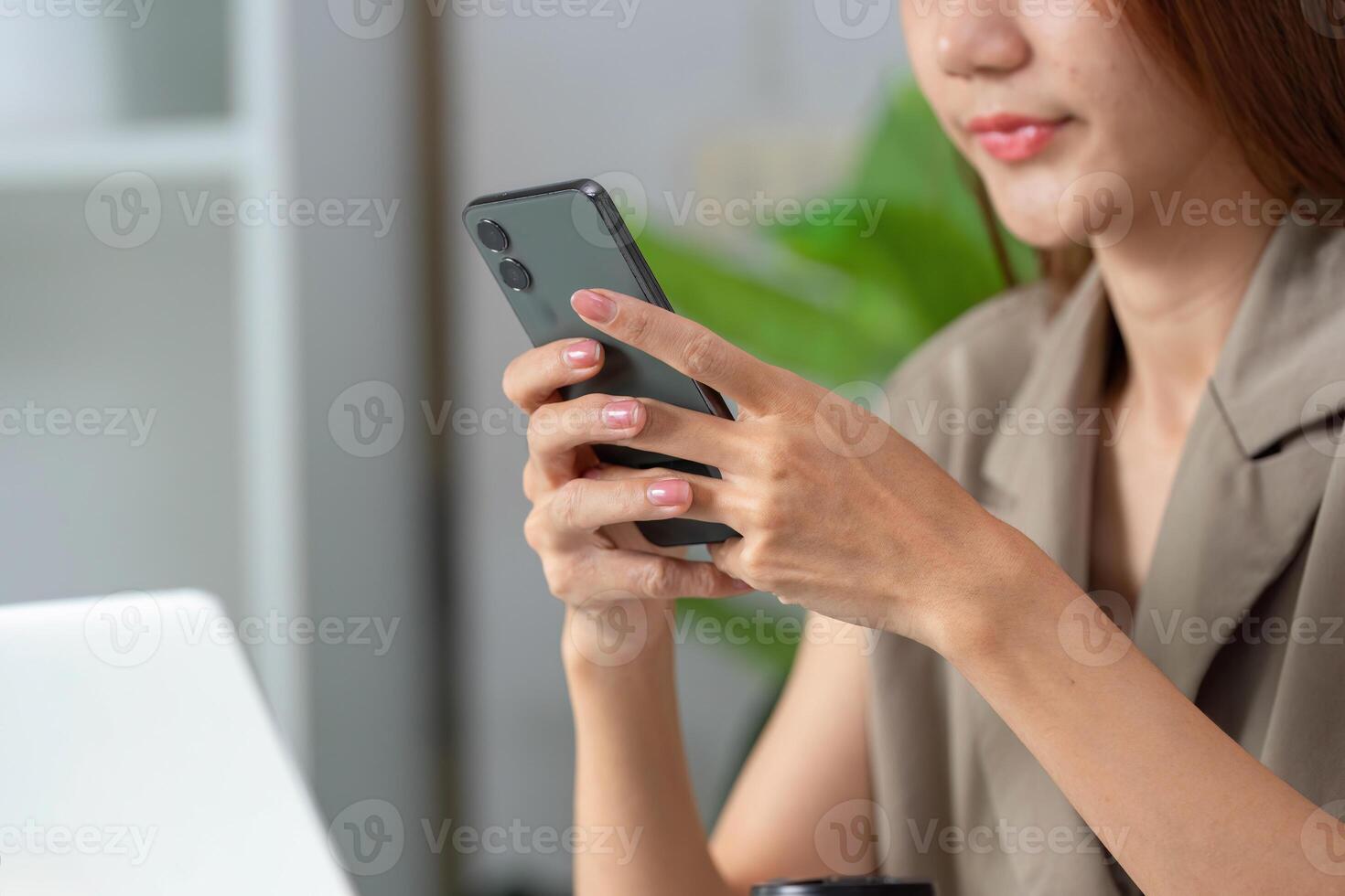 Mobile Technology and Communication. A woman engaging with her smartphone while seated at her desk. photo