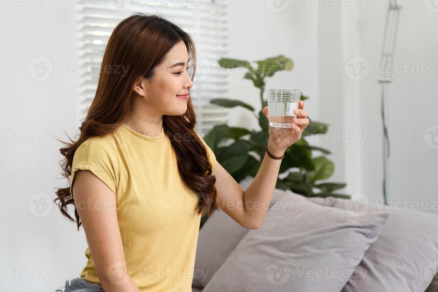Morning Routine and Refreshment. A woman relishing a moment with a glass of water after waking up. photo