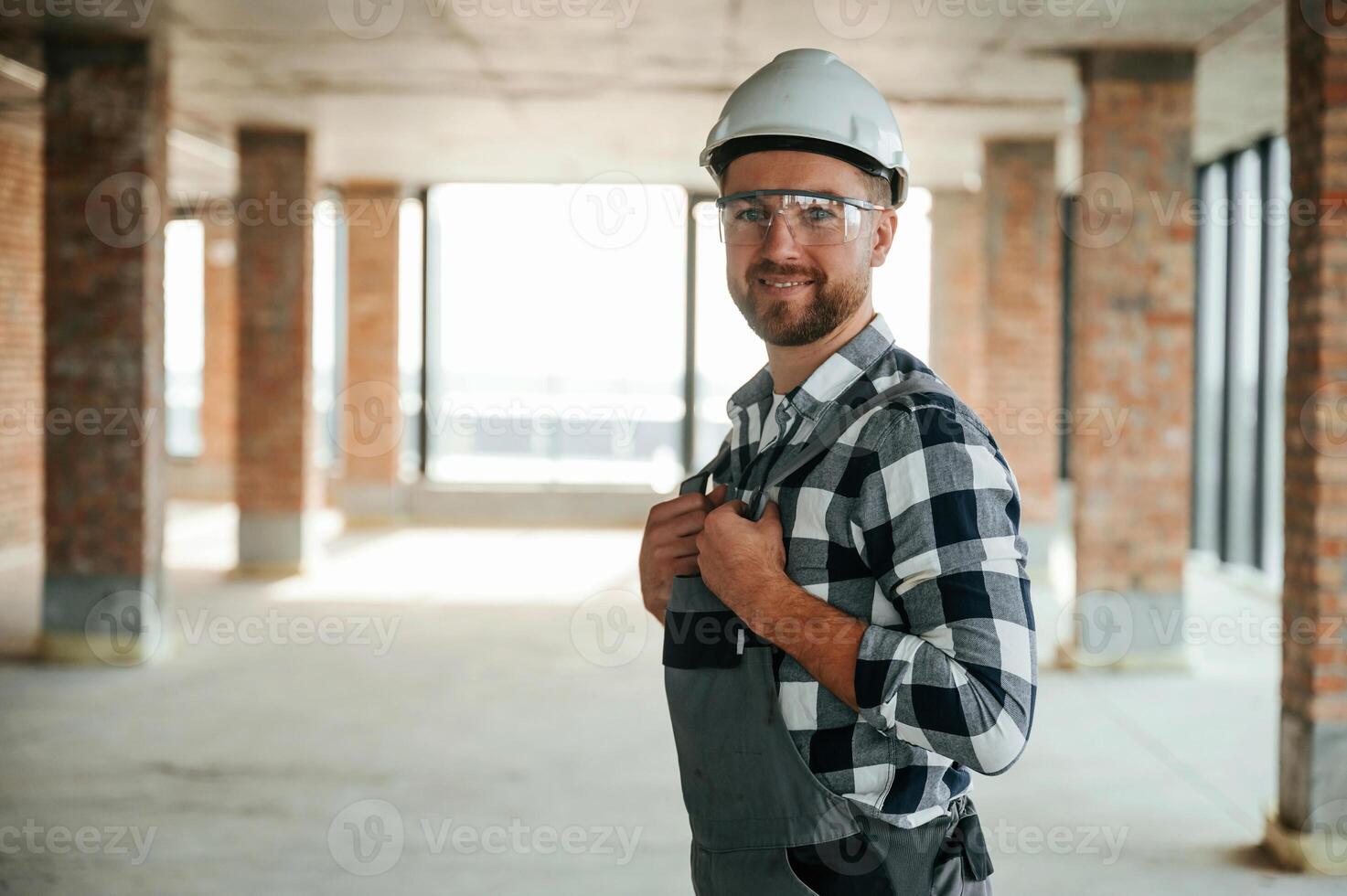 Positive ,,smiling construction worker in uniform in empty unfinished room photo