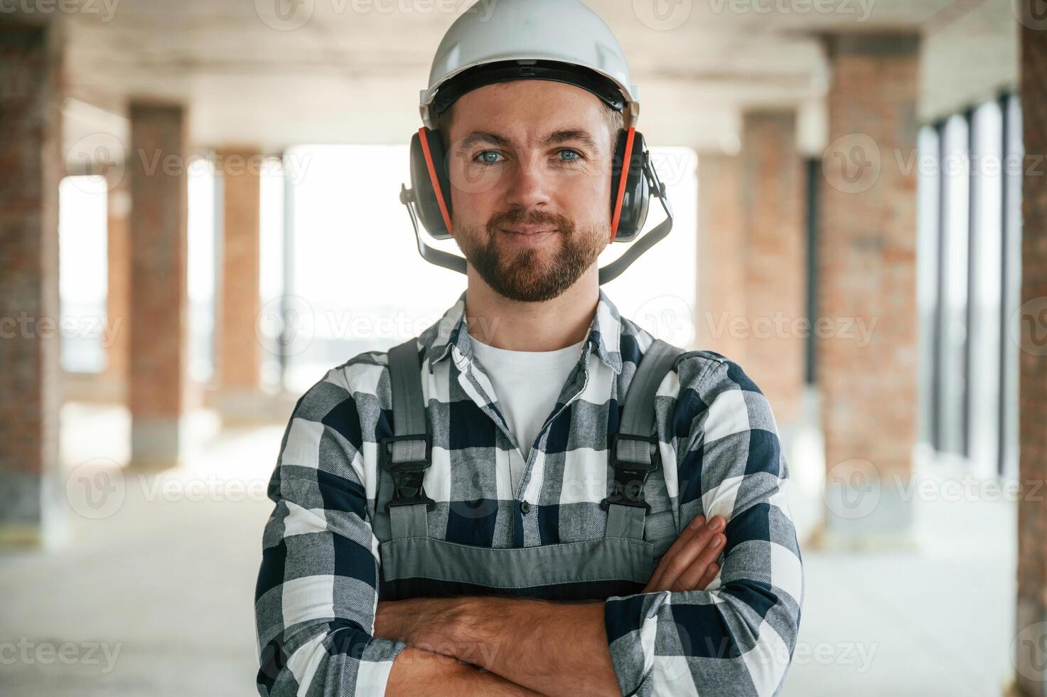 Portrait, in hard hat... Construction worker in uniform in empty unfinished room photo