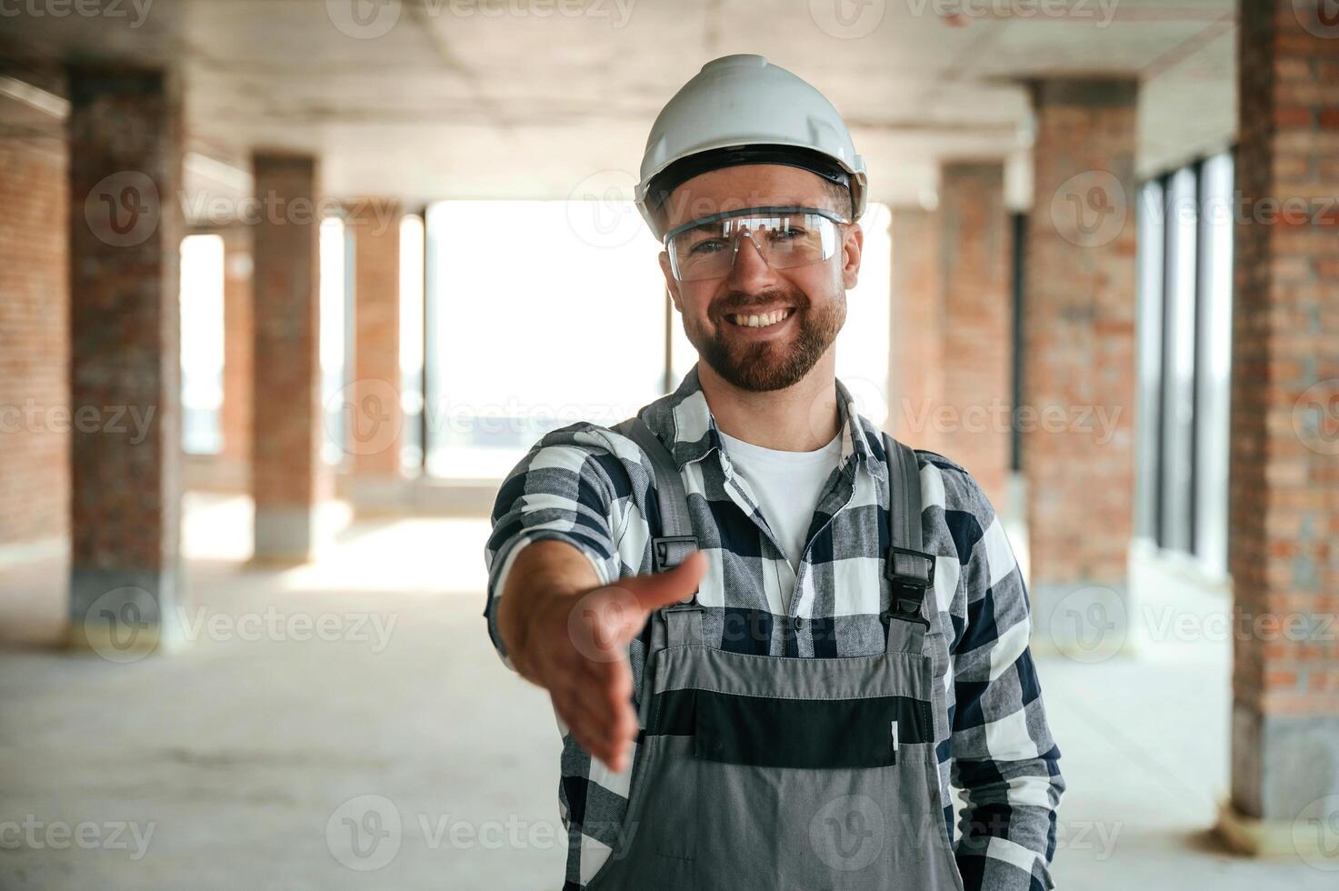 Positive smiling ,construction worker in uniform in empty unfinished room photo