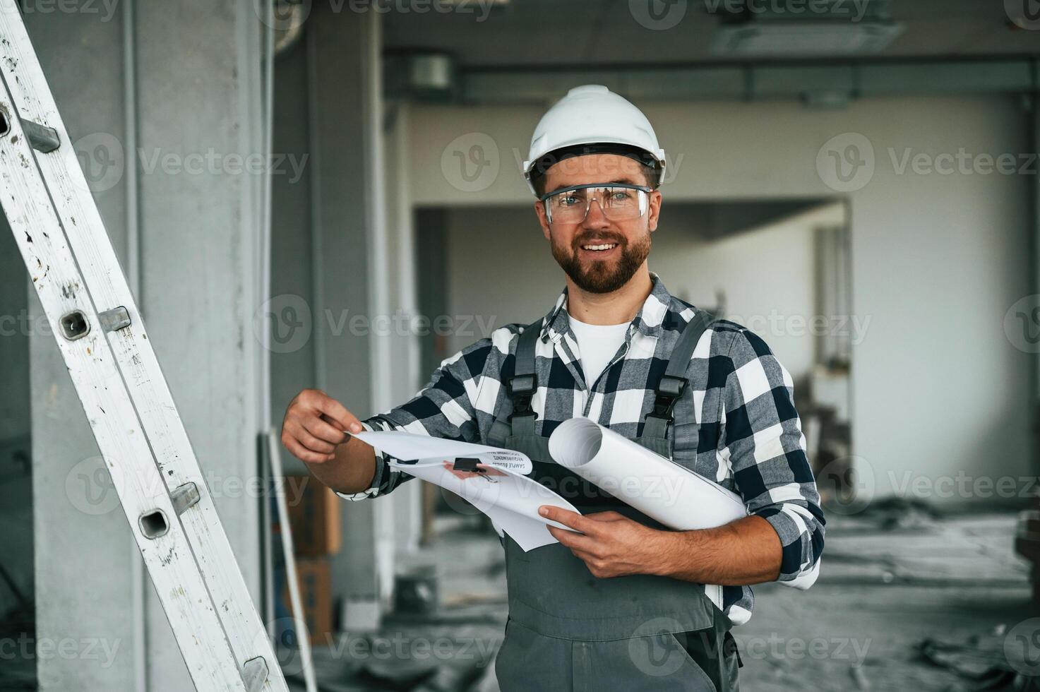 Manager, is with plan in hands. Repairman in uniform is in the unfinished building photo