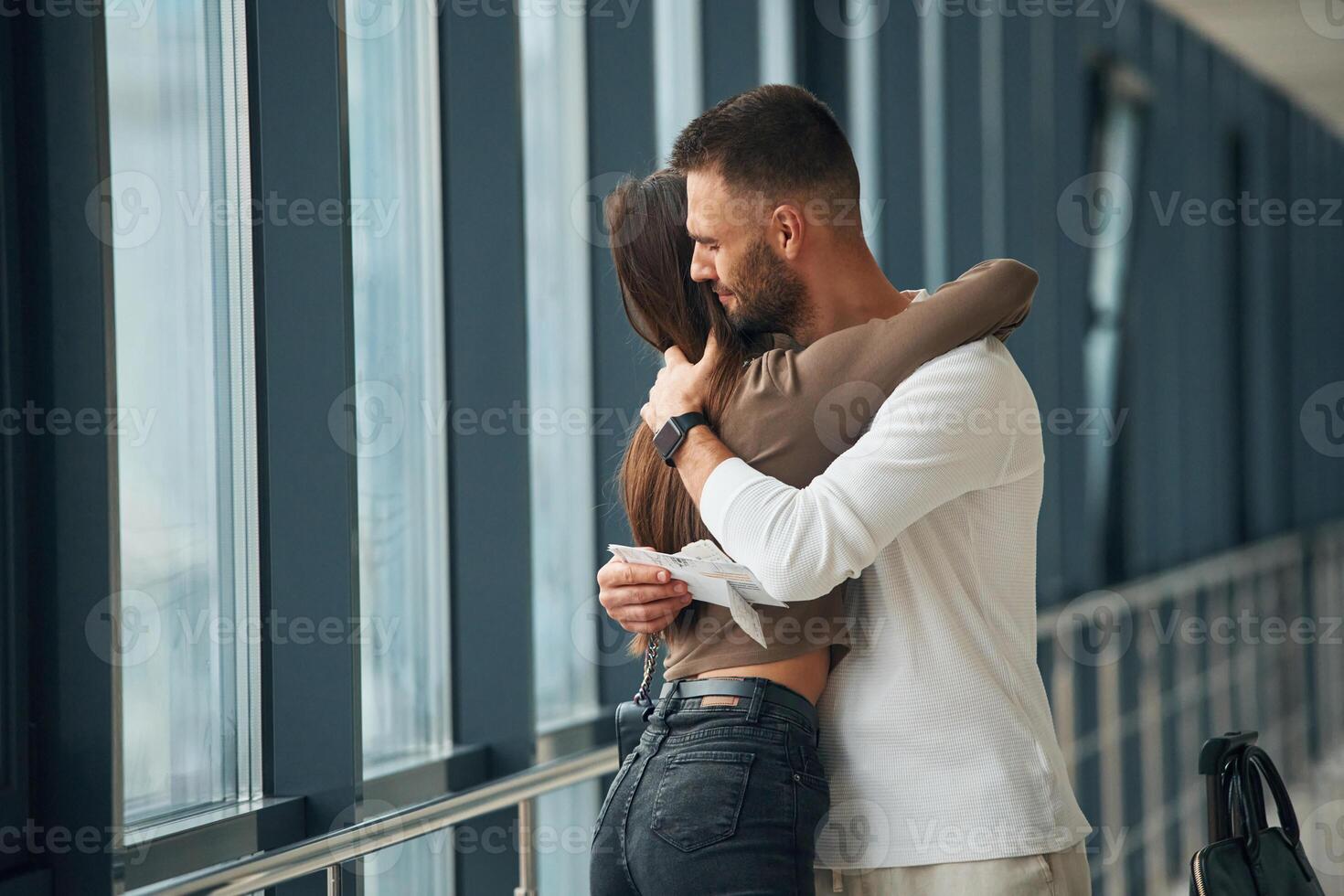 Preparing for long flight, embracing ,each other. Couple are in the airport hall together photo