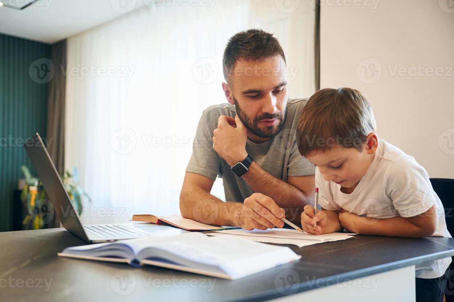 Doing homework. Father and son, are, at home by the table photo