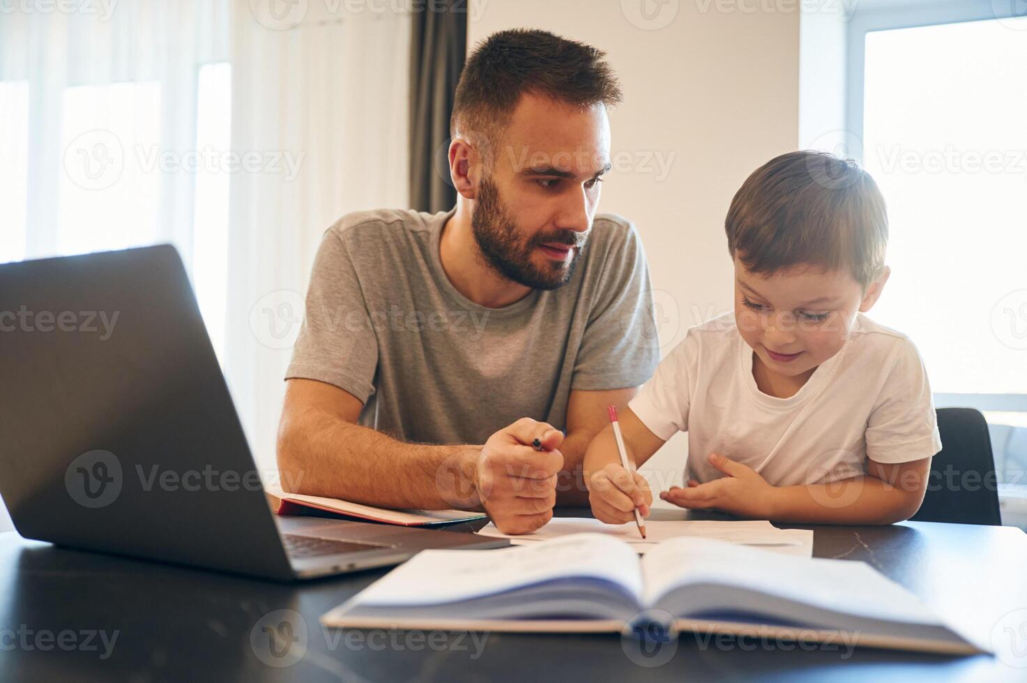 Doing homework., Father ,and son are at home by the table photo