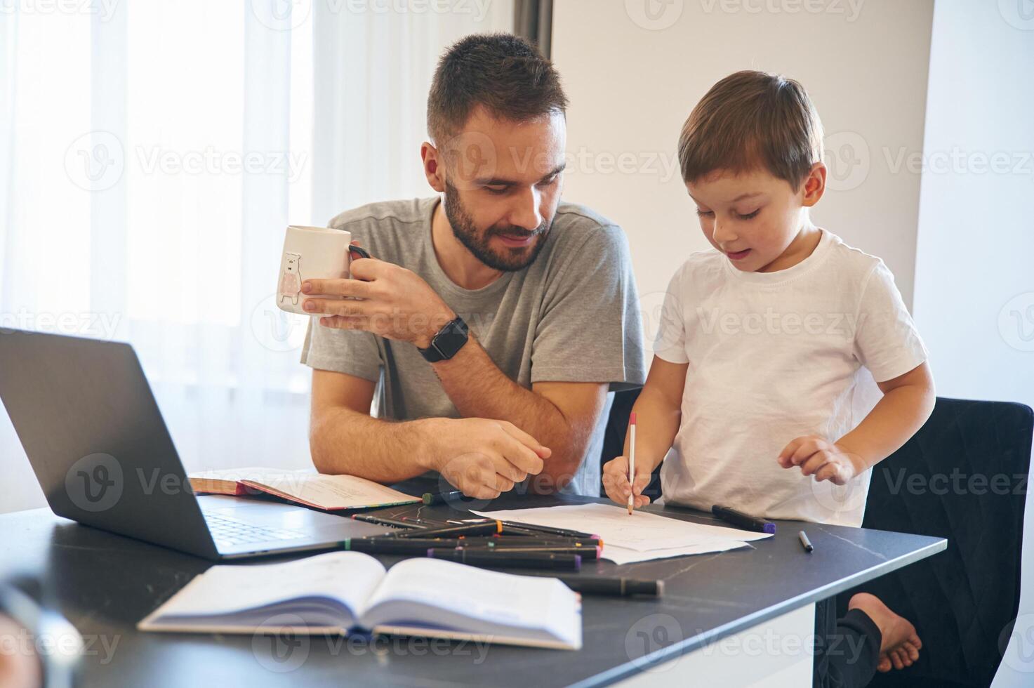 Doing homework... Father and son are at home by the table photo