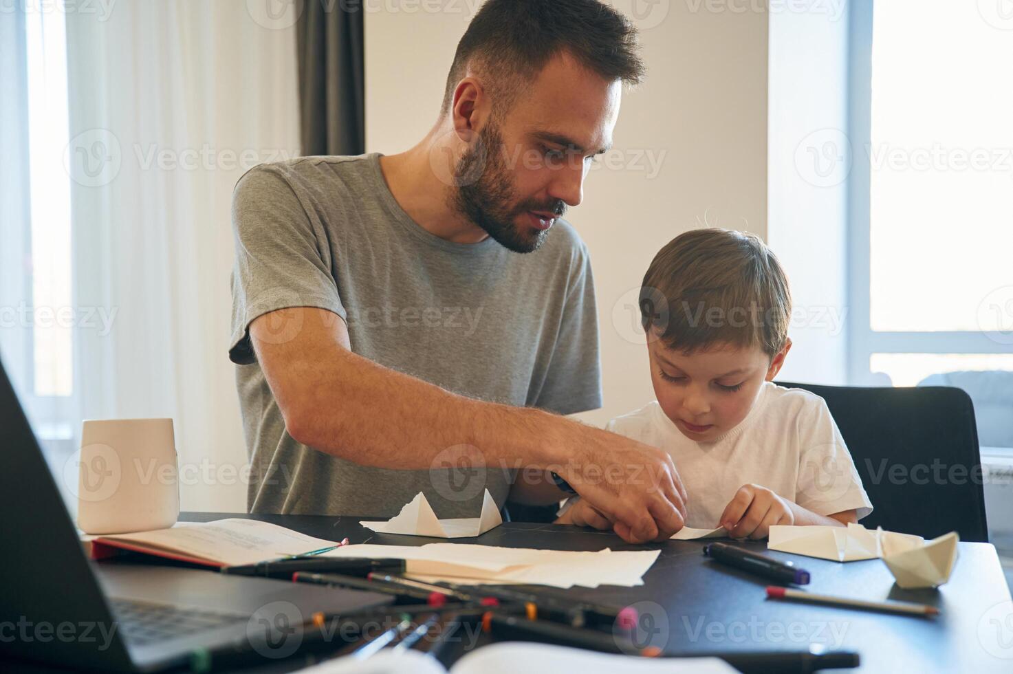 Learning how, to, craft origami. Father and son are at home by the table photo