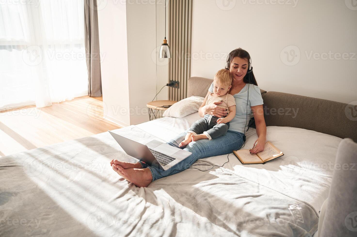 On the comfortable bed. Mother ,with her little son is at home in domestic room photo