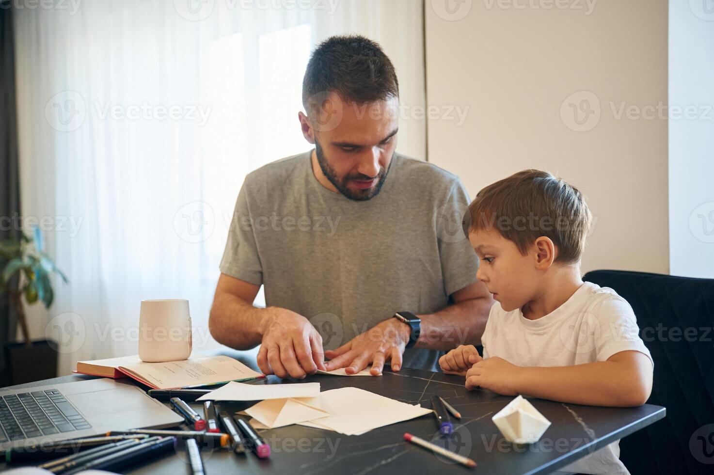Learning ,,how to craft origami. Father and son are at home by the table photo