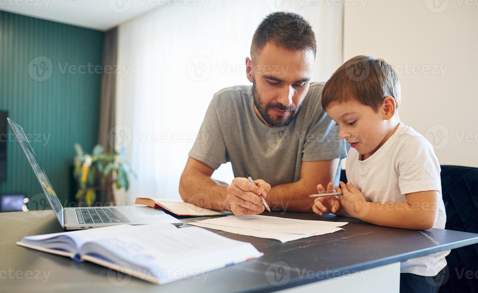 Writing, the homework. Father and son are at home by the table photo