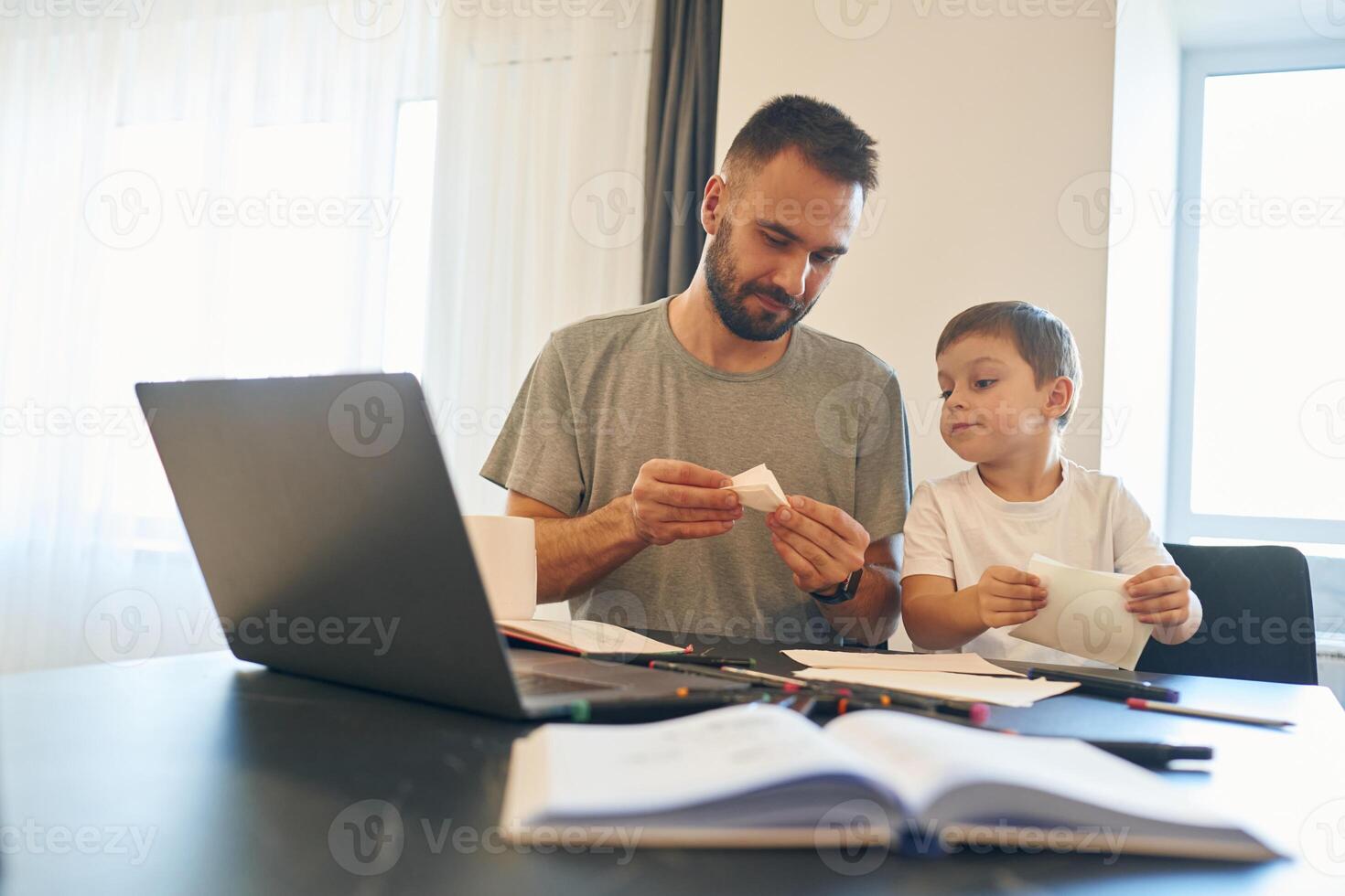 Learning, how to craft origami. Father and son are at home by the table photo