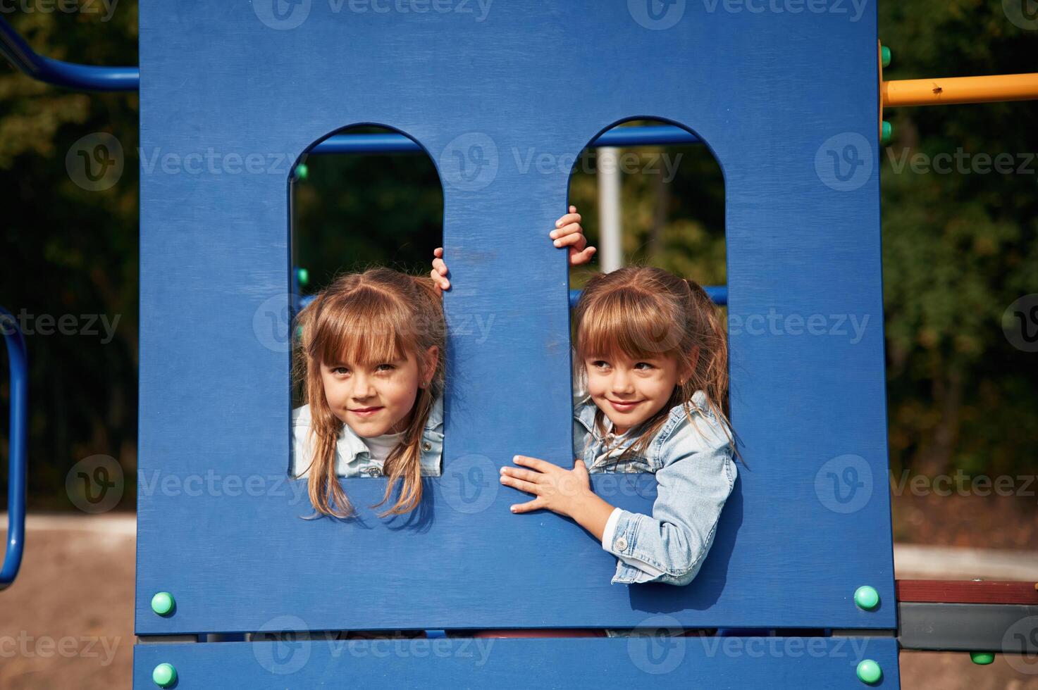 Hiding behind blue construction, smiling... Kids are having fun on the playground photo