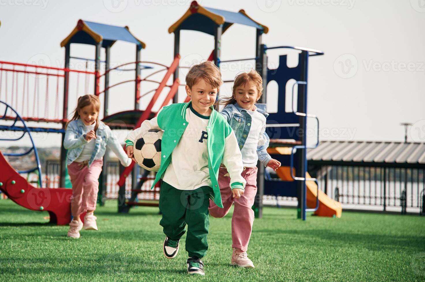 Holding soccer ball in hand, running... Kids are having fun on the playground photo