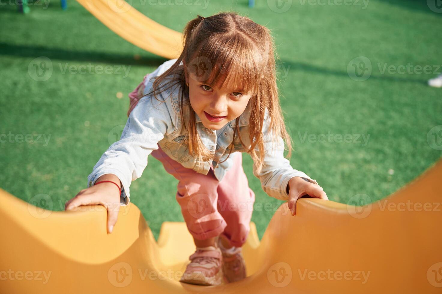 On a ,playground slide. Little girl is having fun on photo
