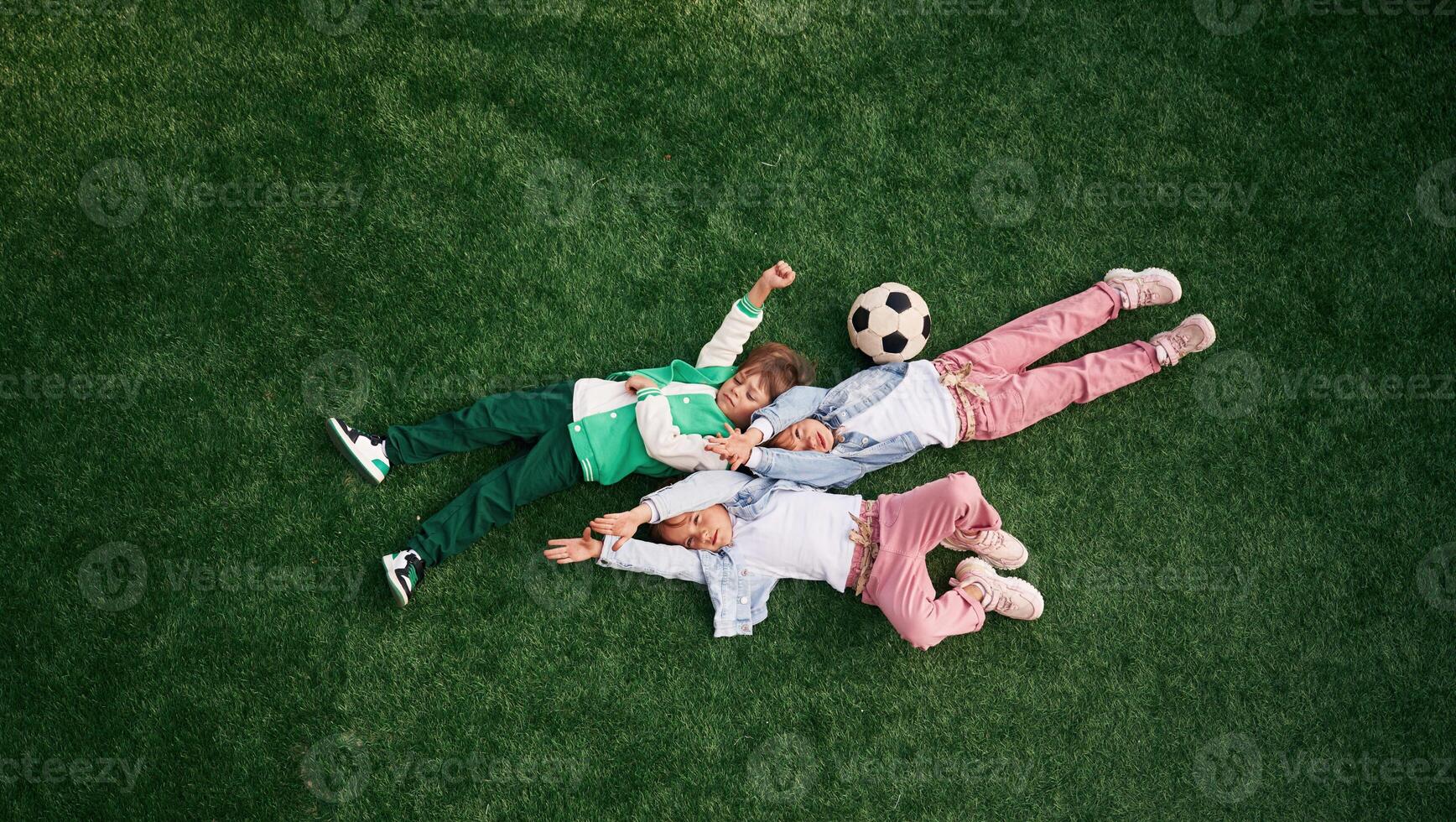 Lying down. Kids are having fun on the green soccer field together photo