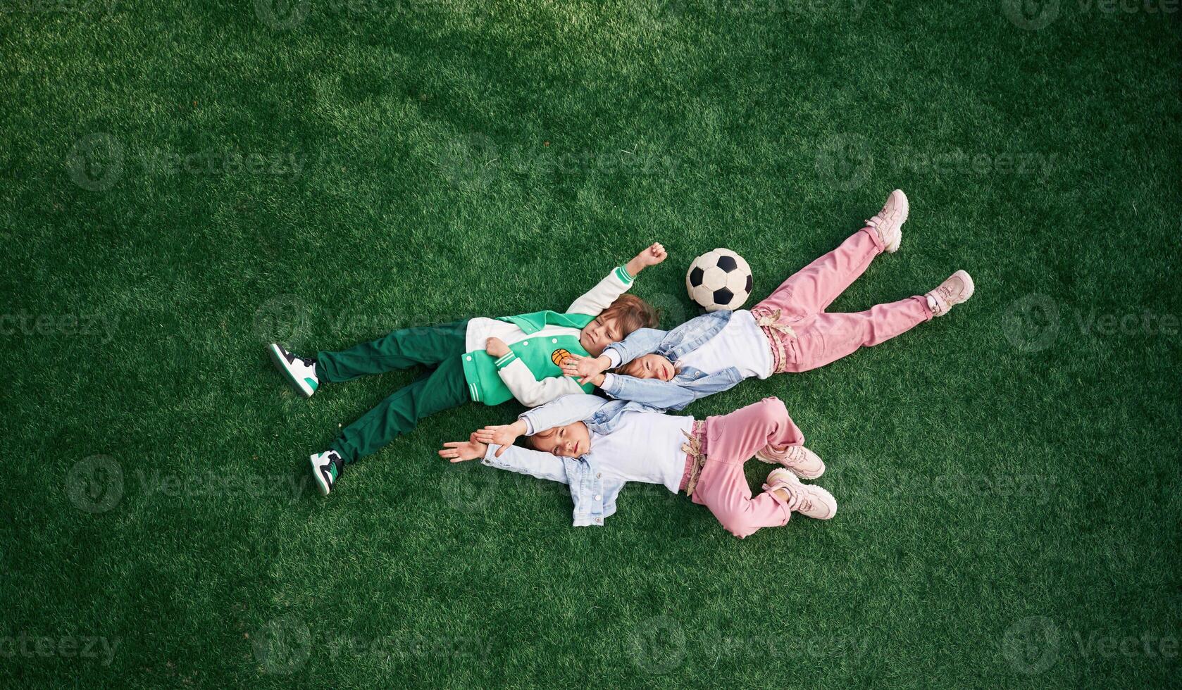 Top view. Lying down. Kids are having fun on the green soccer field together photo