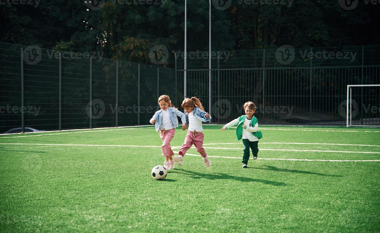 Running ,with ,ball. Kids are having fun on the green soccer field together photo