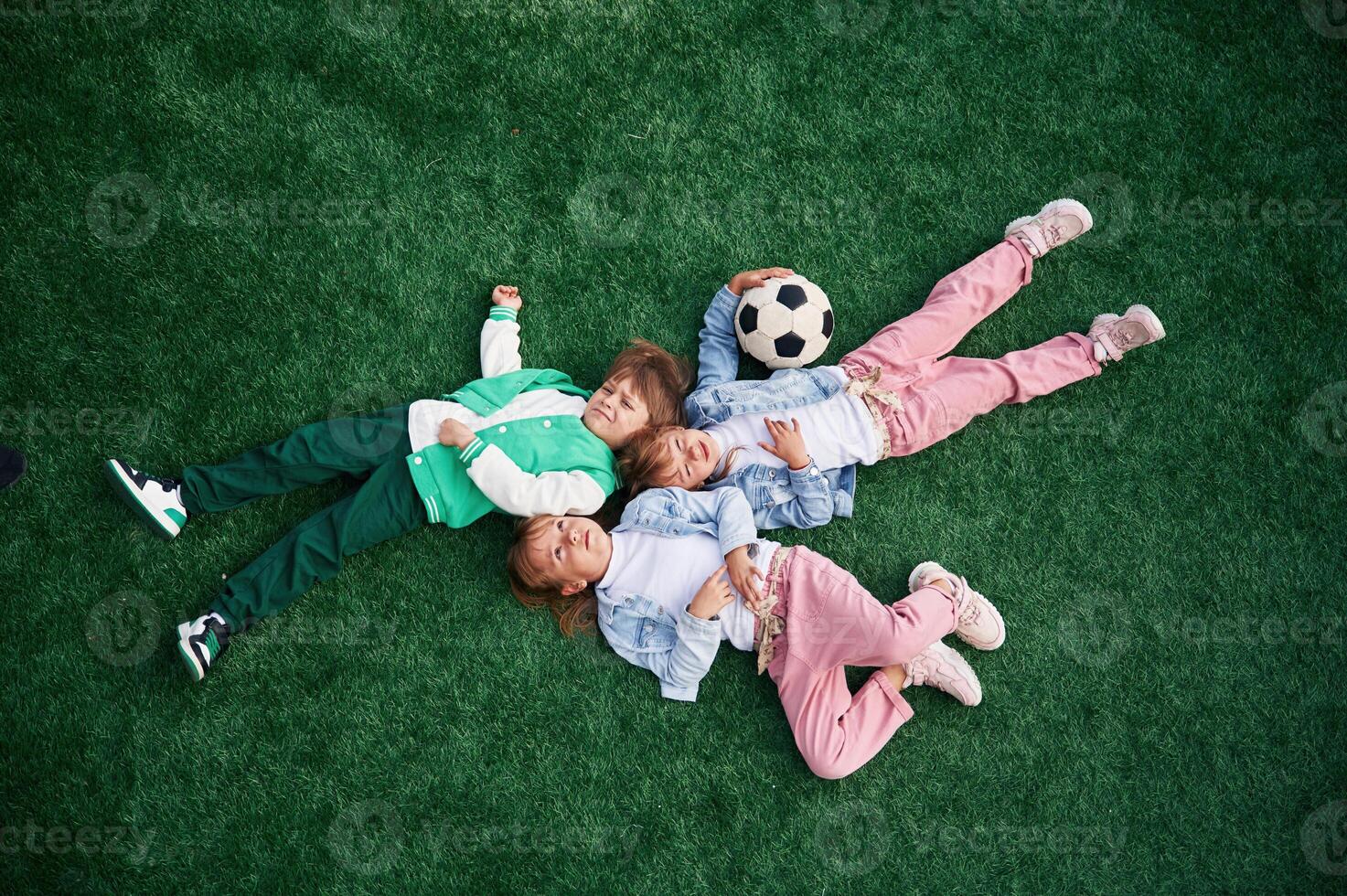 Top view. Lying down. Kids, are having ,fun on the green soccer field together photo