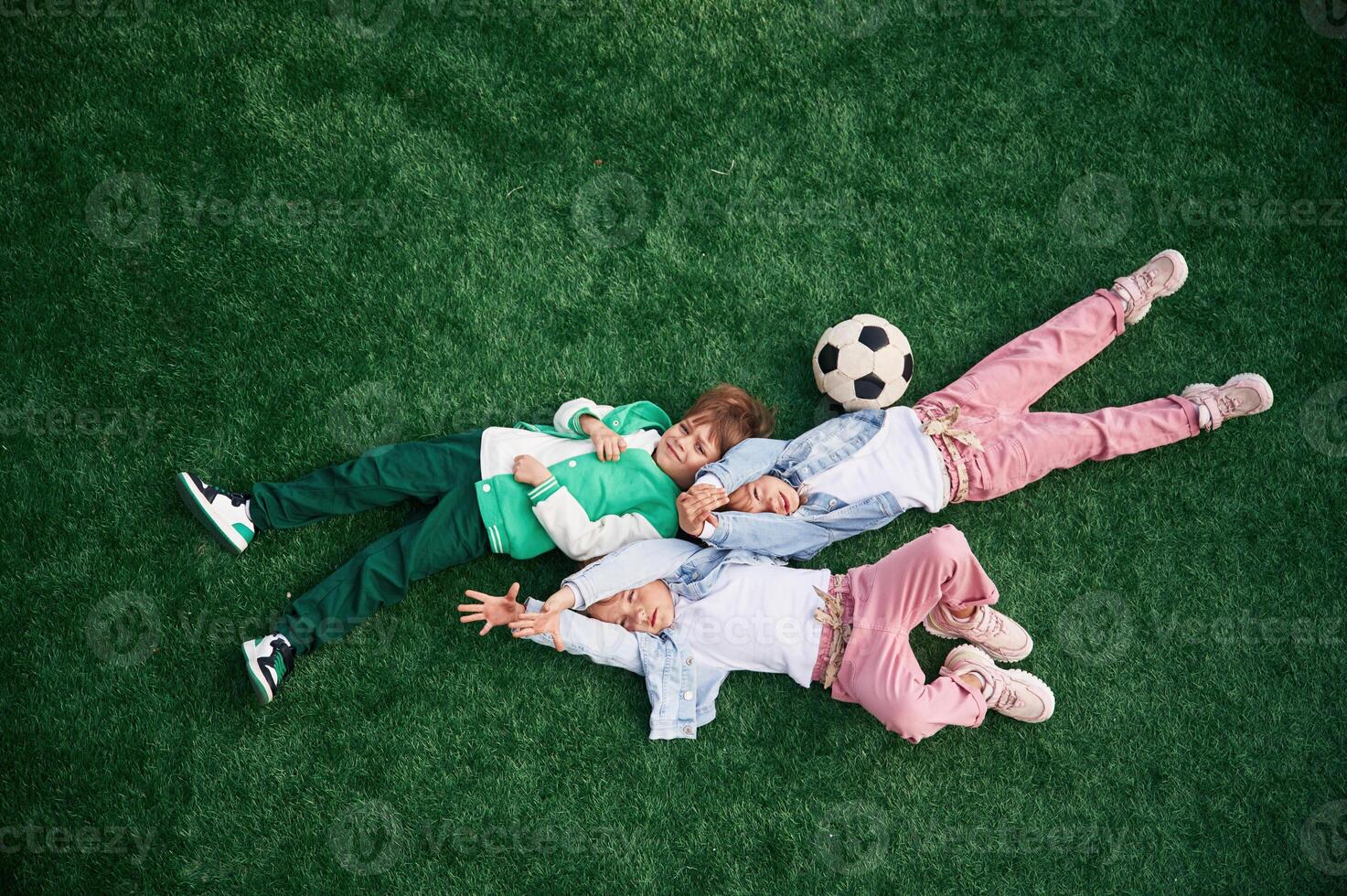 Top view. Lying down. Kids are having, fun ,on the green soccer field together photo