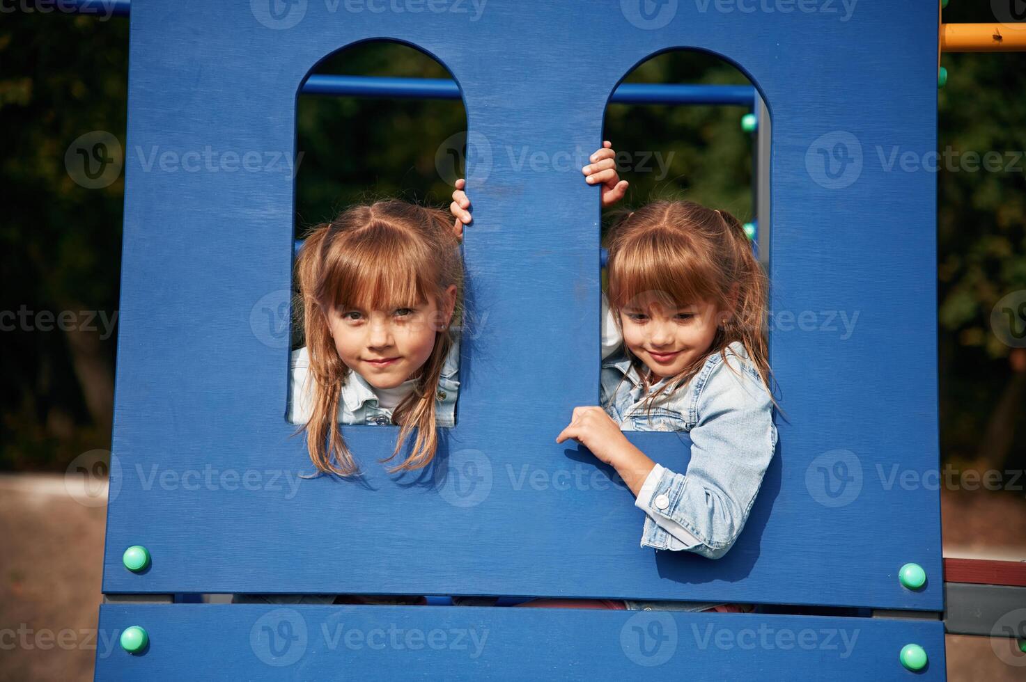 Hiding behind blue construction, ,smiling. Kids are having fun on the playground photo