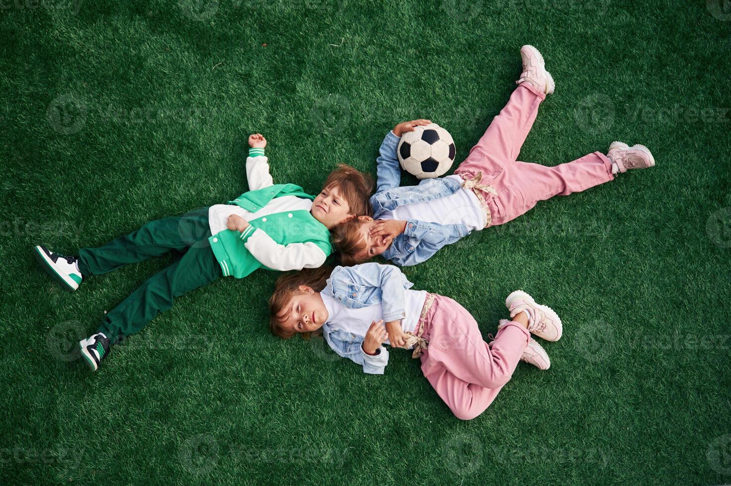 Top view. Lying down. Kids are having fun, on the green soccer field together photo