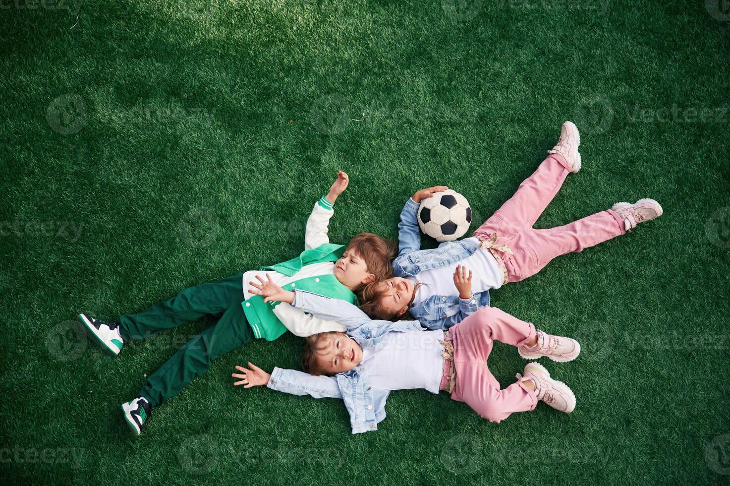 Top view. Lying down. Kids are, having fun on the green soccer field together photo