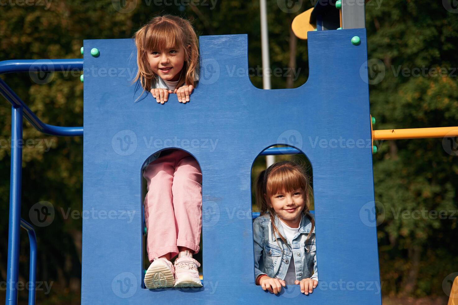 Hiding behind blue construction, smiling,. Kids are having fun on the playground photo