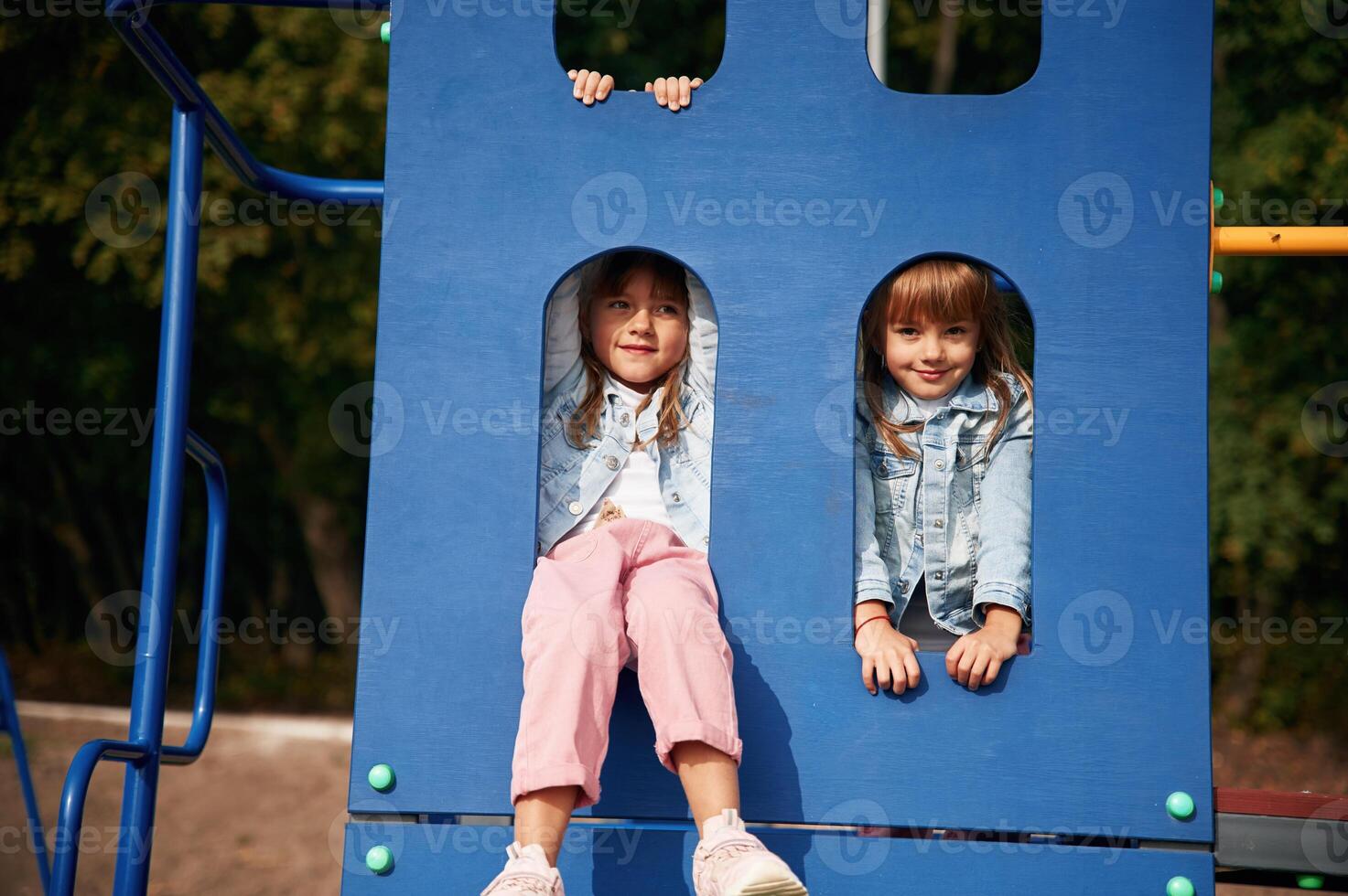 Hiding behind, blue construction, smiling. Kids are having fun on the playground photo