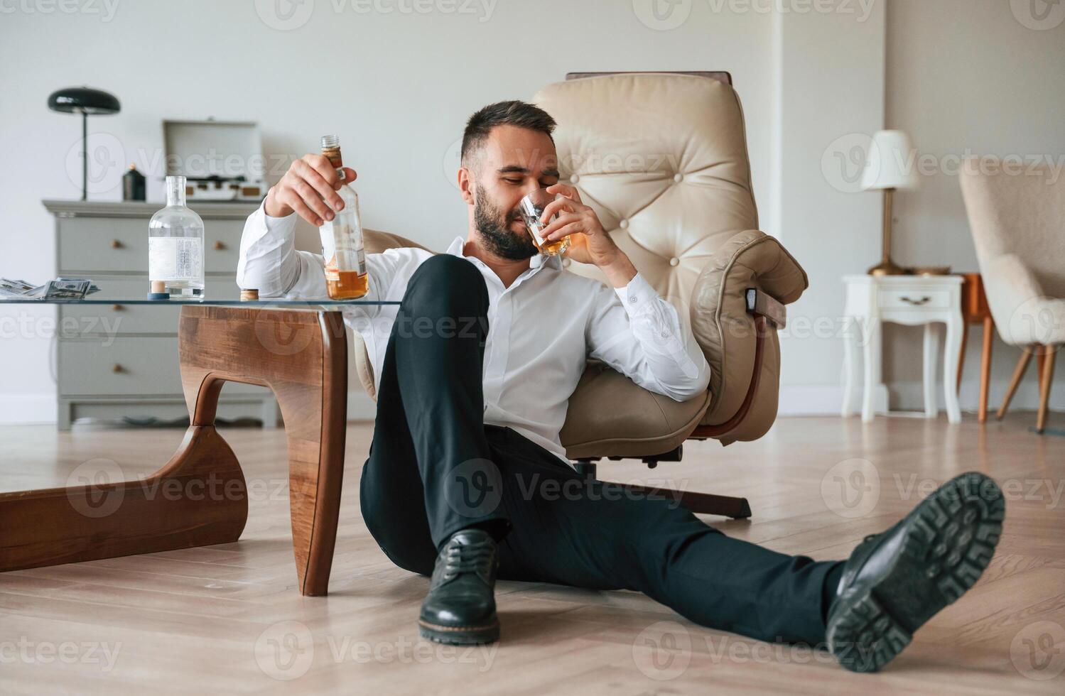 Sitting on the floor, sad. Upset young man drinker alcoholic is indoors photo