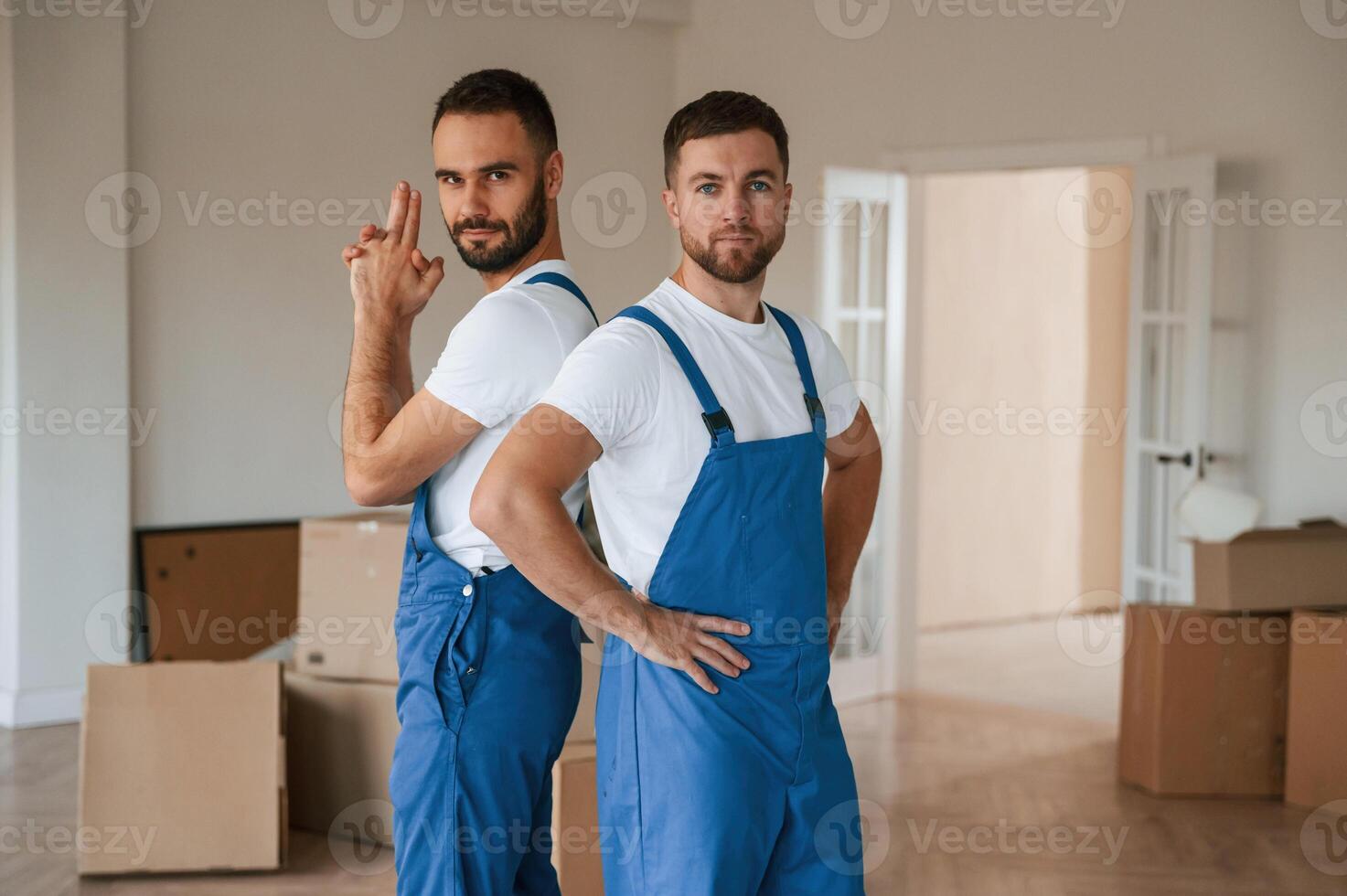Standing and posing. Two moving service,, employees in a room photo