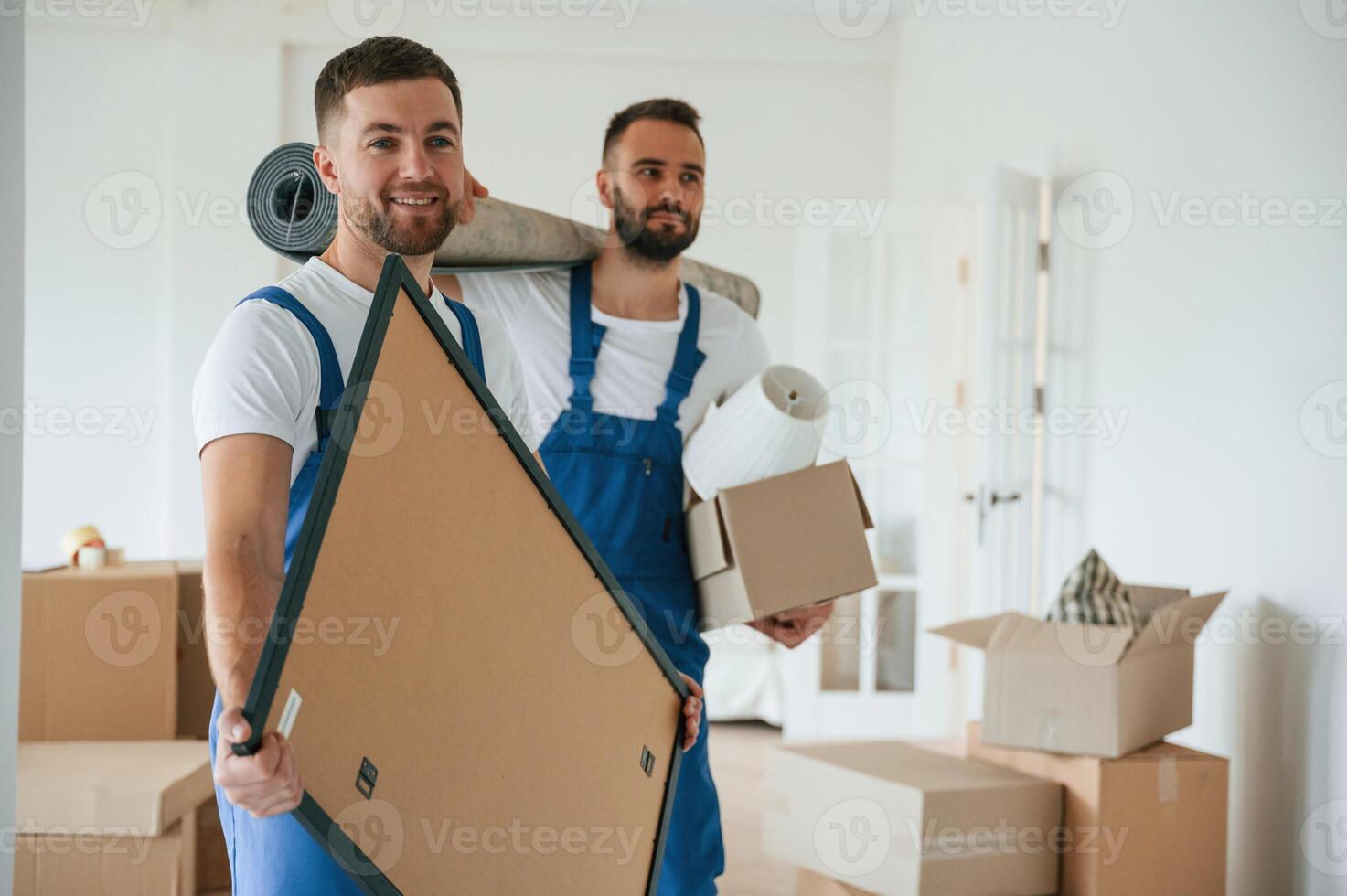 Painting and mat in hands. Two moving, service employees in a room photo