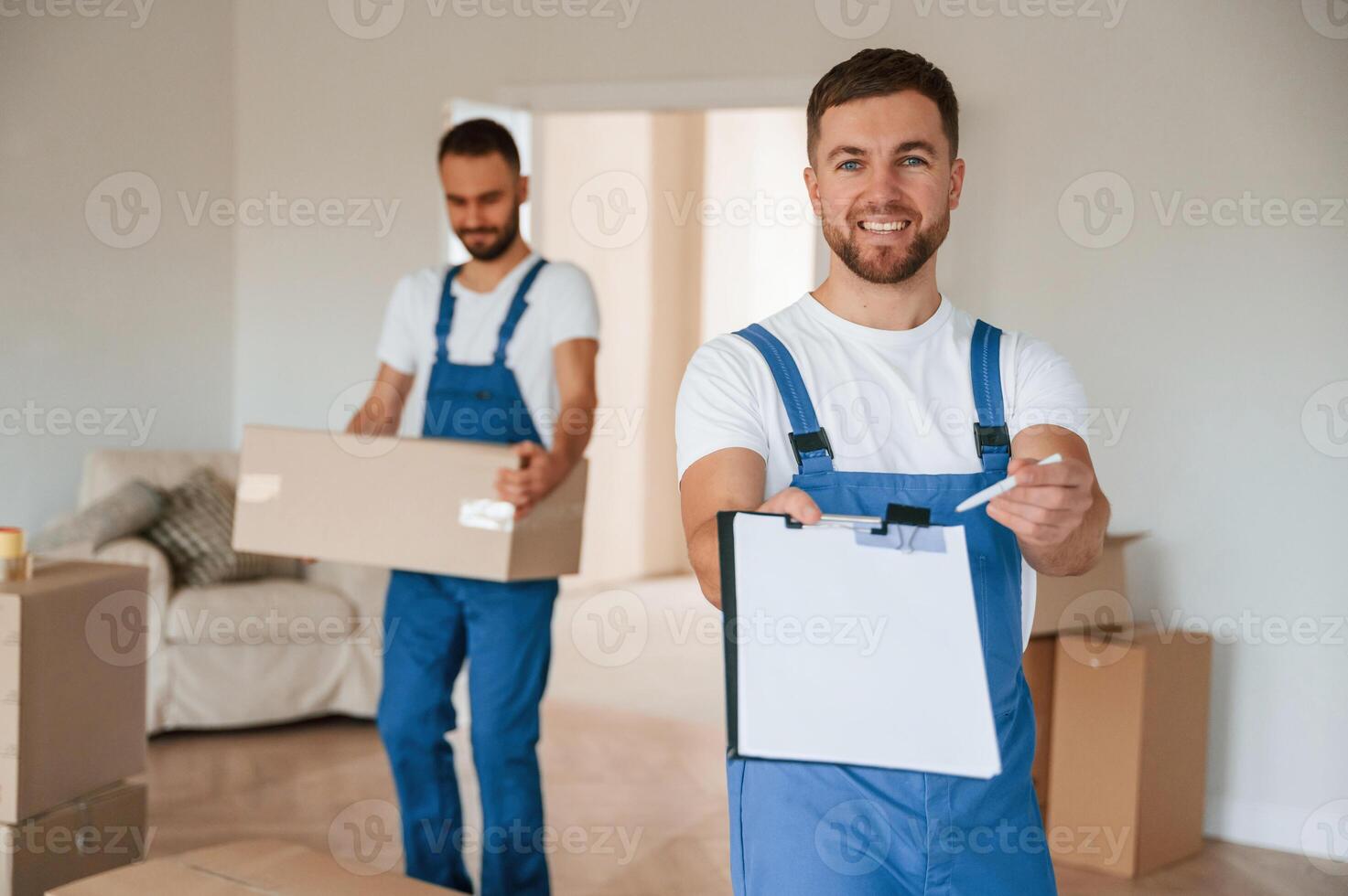 Sign in the ,documents. Two moving, service employees in a room photo