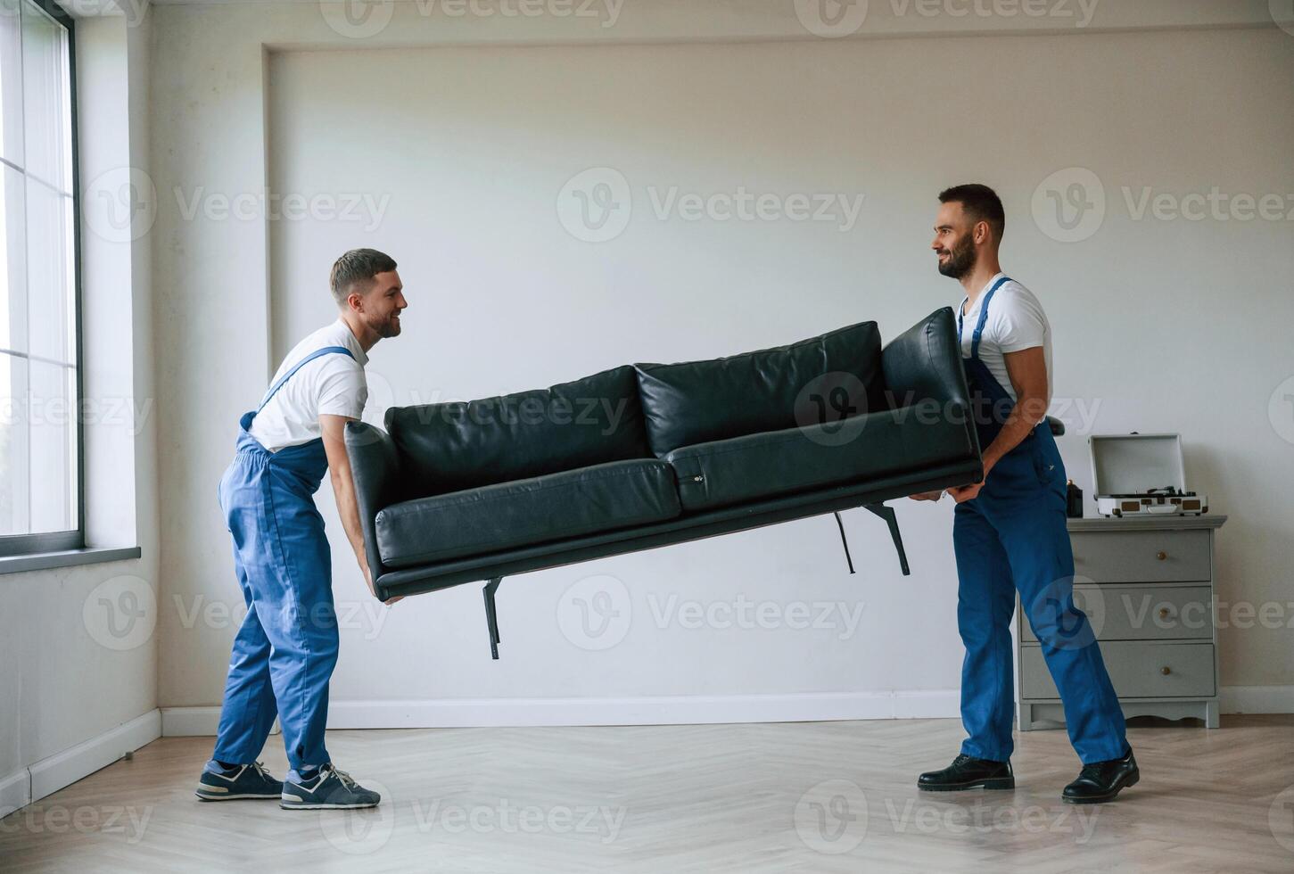 Sofa in hands. Two, moving ,service employees in a room photo