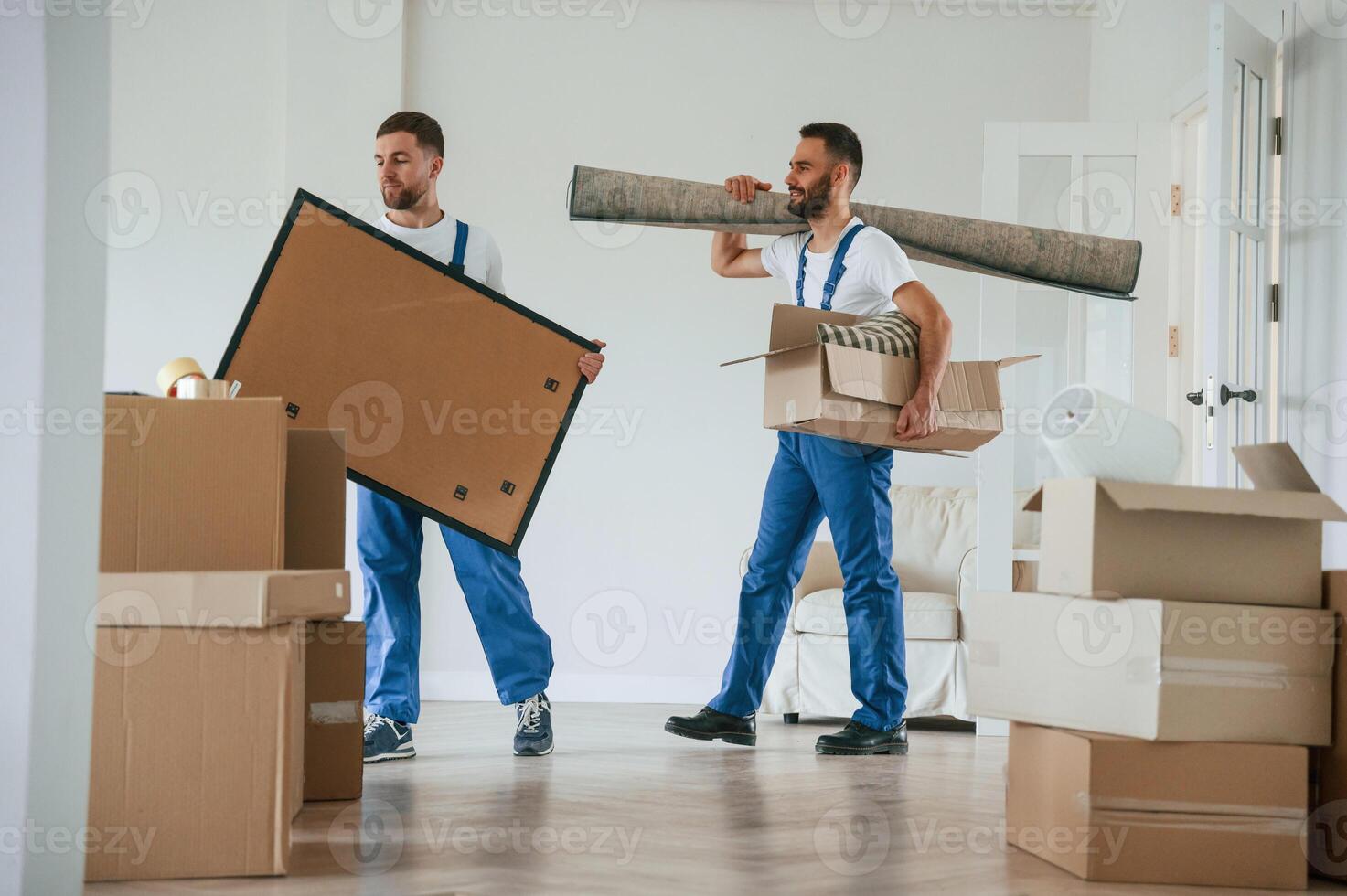 Painting and mat in hands. Two ,moving ,service employees in a room photo