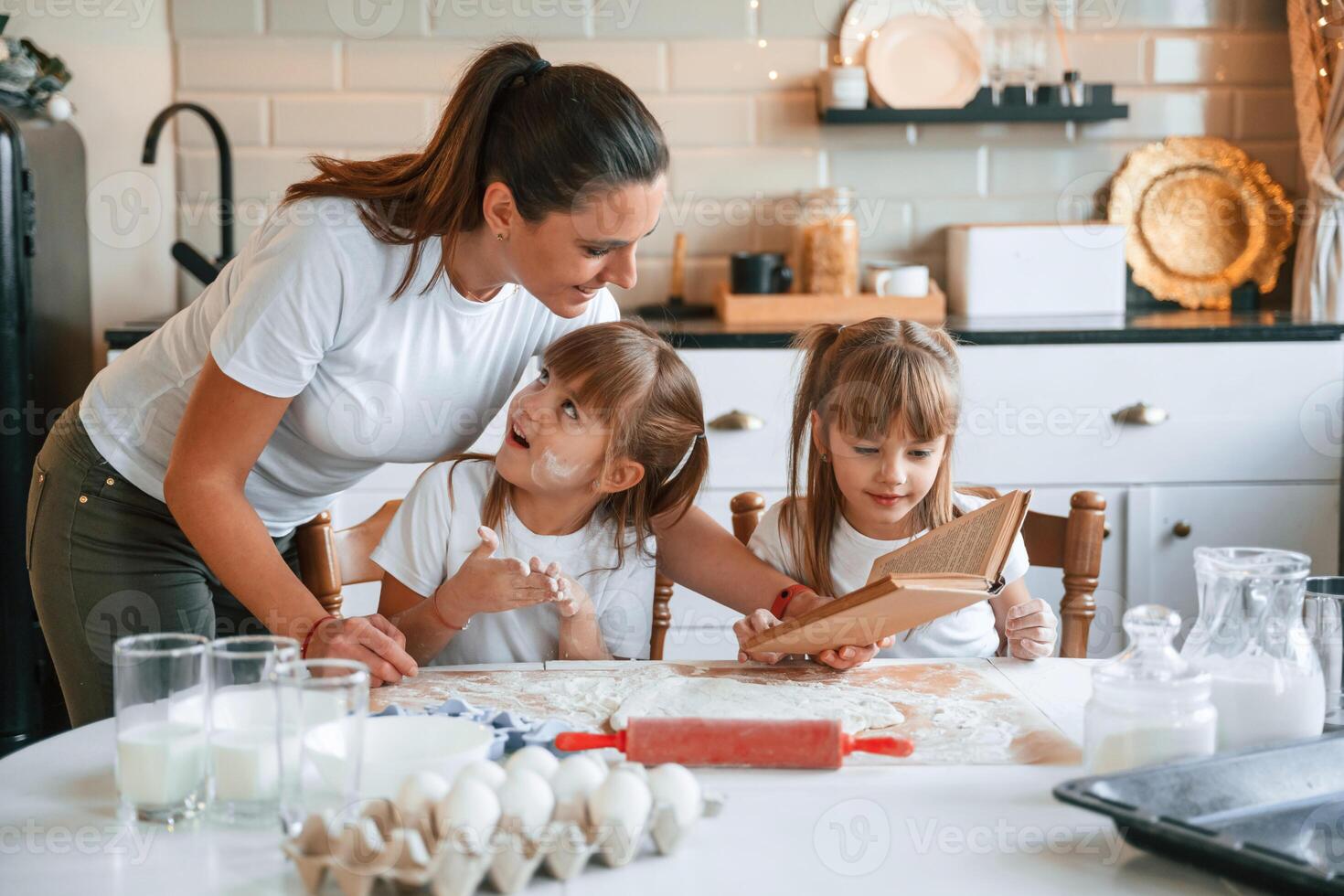 Natural, ingredients.. Mother with her little two daughters is preparing food on the kitchen with garlands together photo