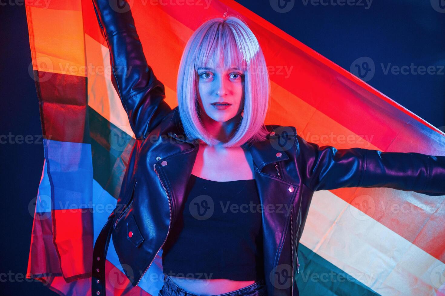 Holding LGBT flag. Woman, with white hair is in studio with neon colors photo