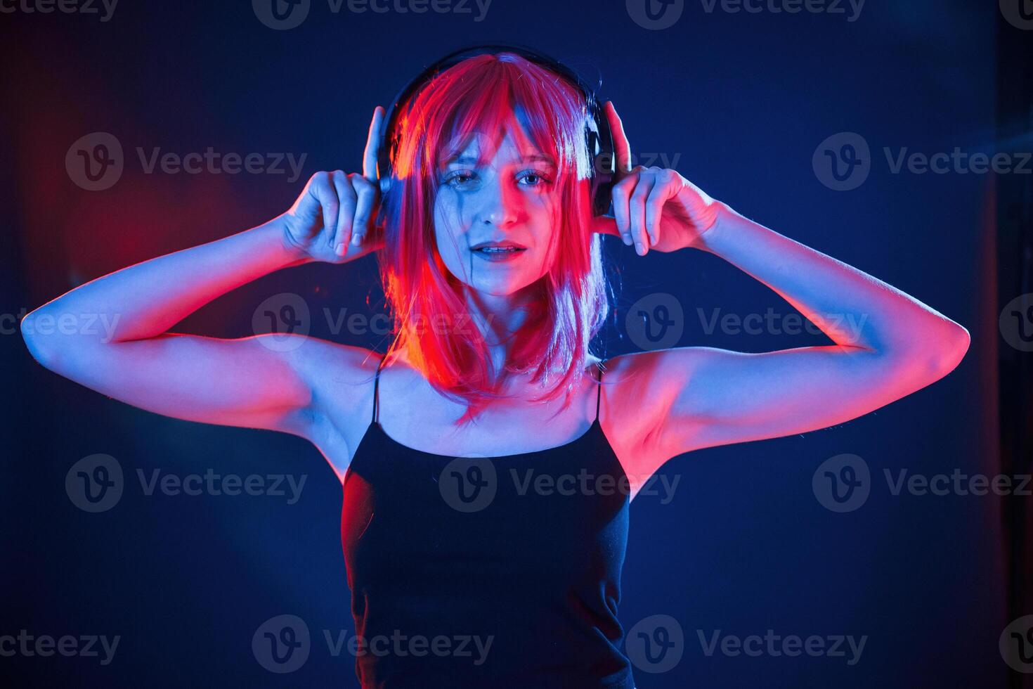 Conception of music, ,,listening in headphones. Woman with white hair is in studio with neon colors photo