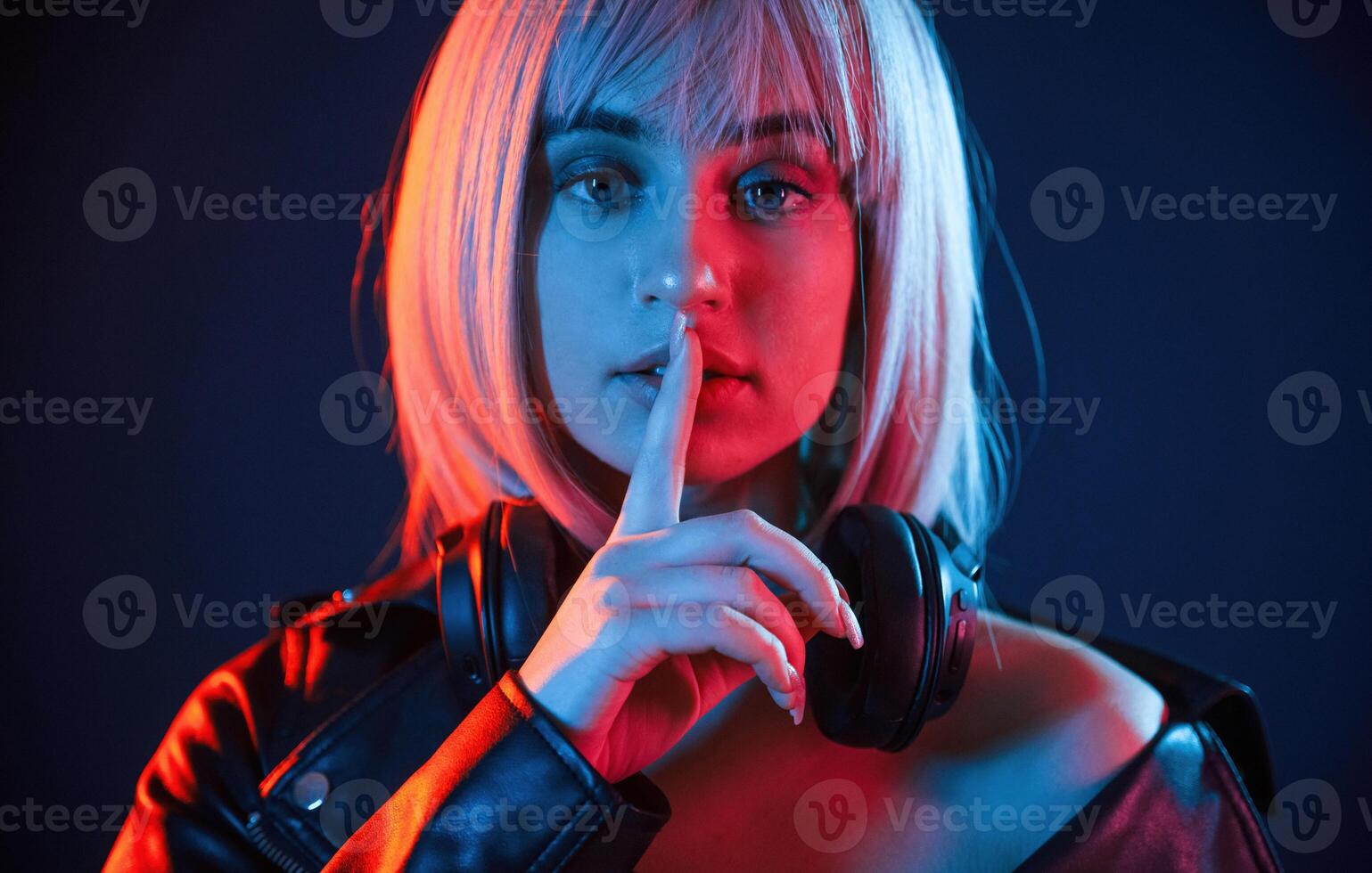 Gesture of be quiet, finger, is ,by, the lips. Woman with white hair is in studio with neon colors photo