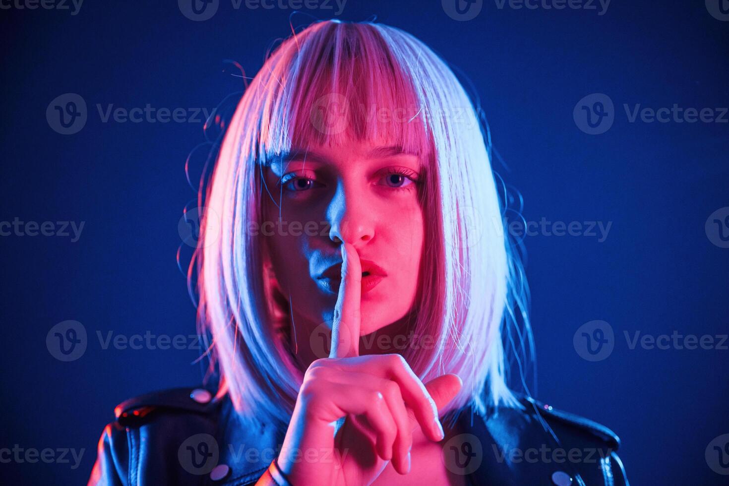 Finger by, the lips,, silence. Woman with white hair is in studio with neon colors photo