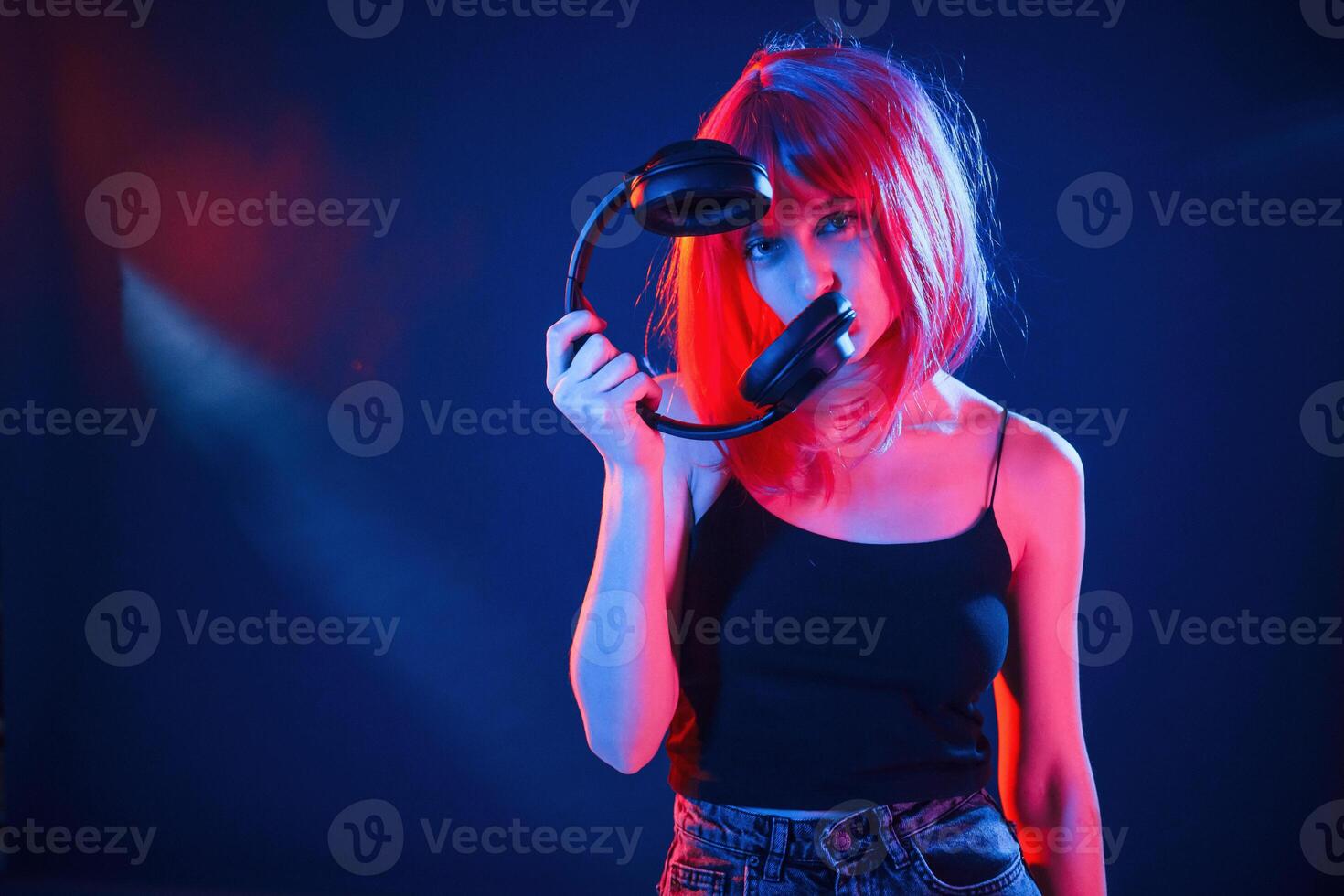 Enjoy, the music, holding headphones. Woman with white hair is in studio with neon colors photo