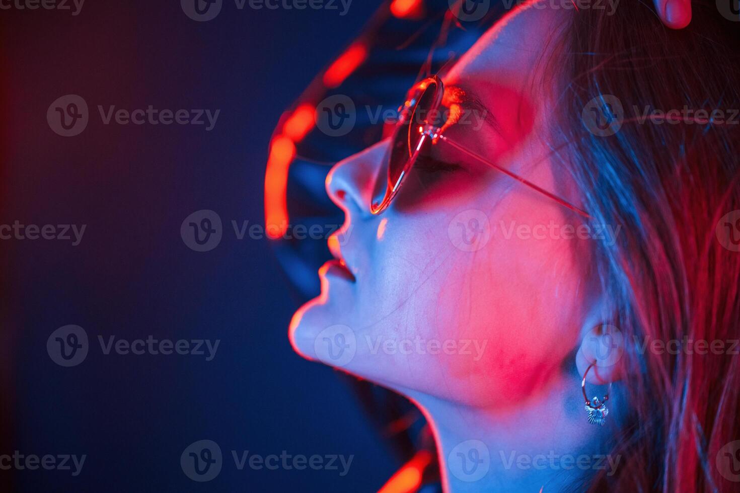 Side view, in eyewear. Cool young woman, portrait in neon colors photo