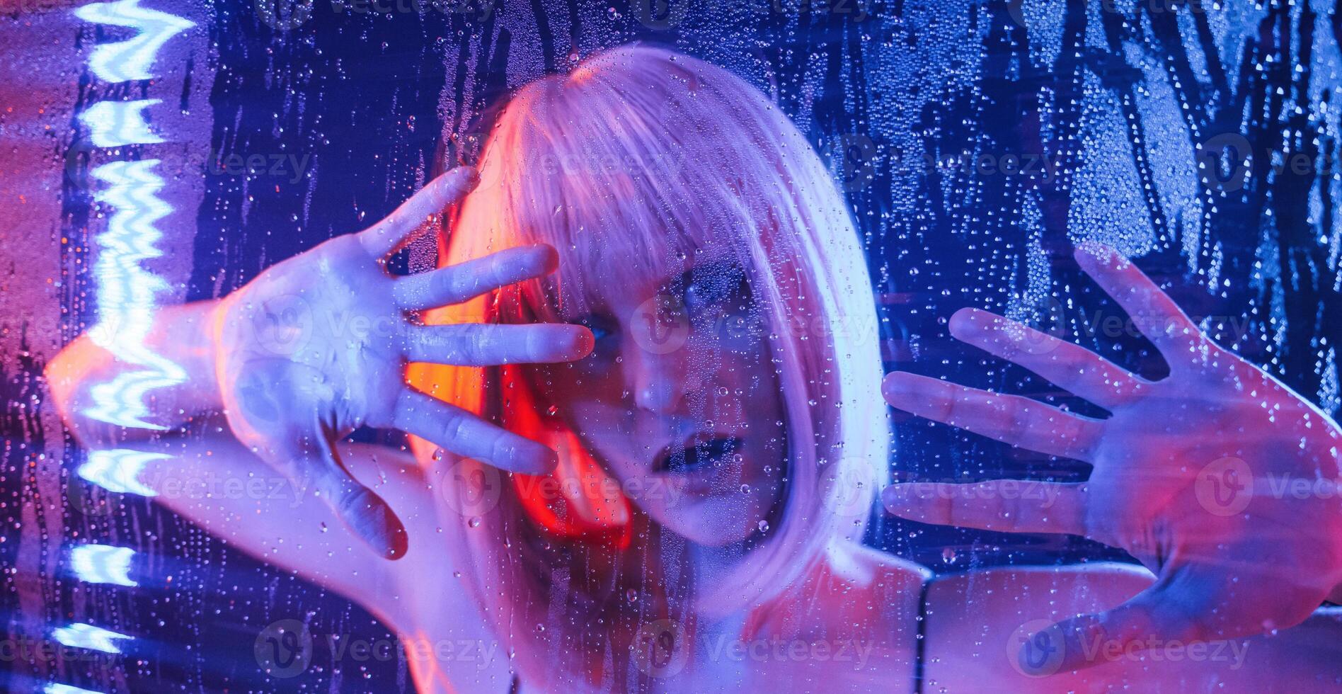 Trapped, inside,, with hands on surface. Stylish woman with white hair is behind wet transparent plastic sheet photo
