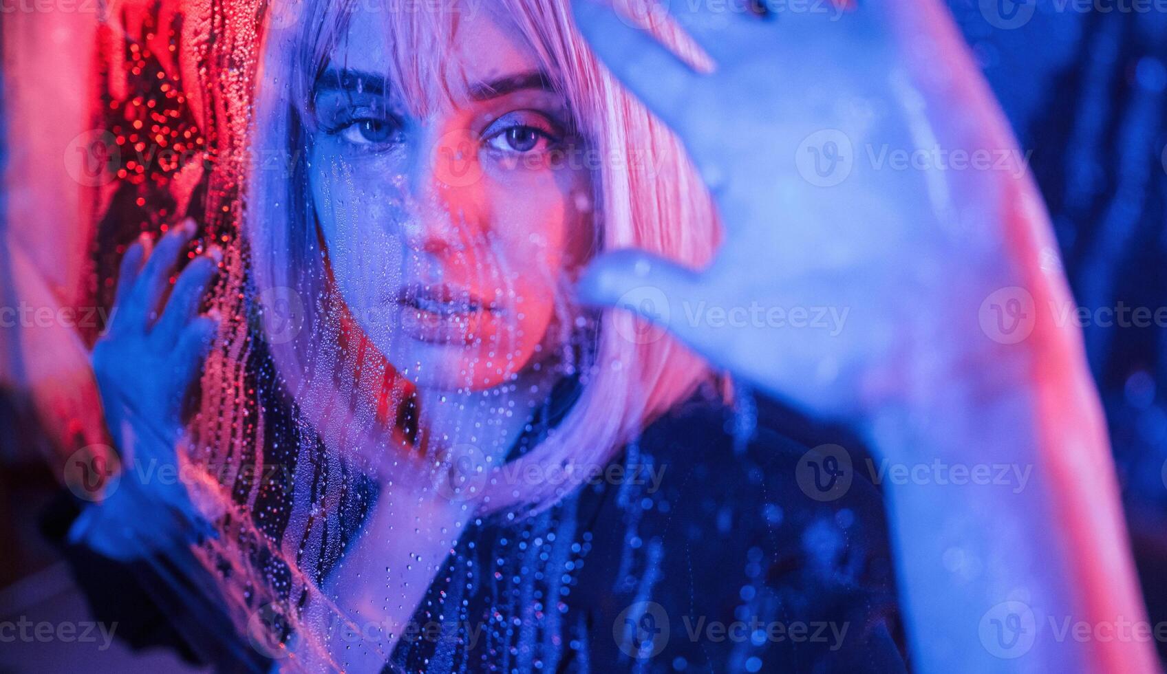 Focused, close, up view. Stylish woman with white hair is behind wet transparent plastic sheet photo