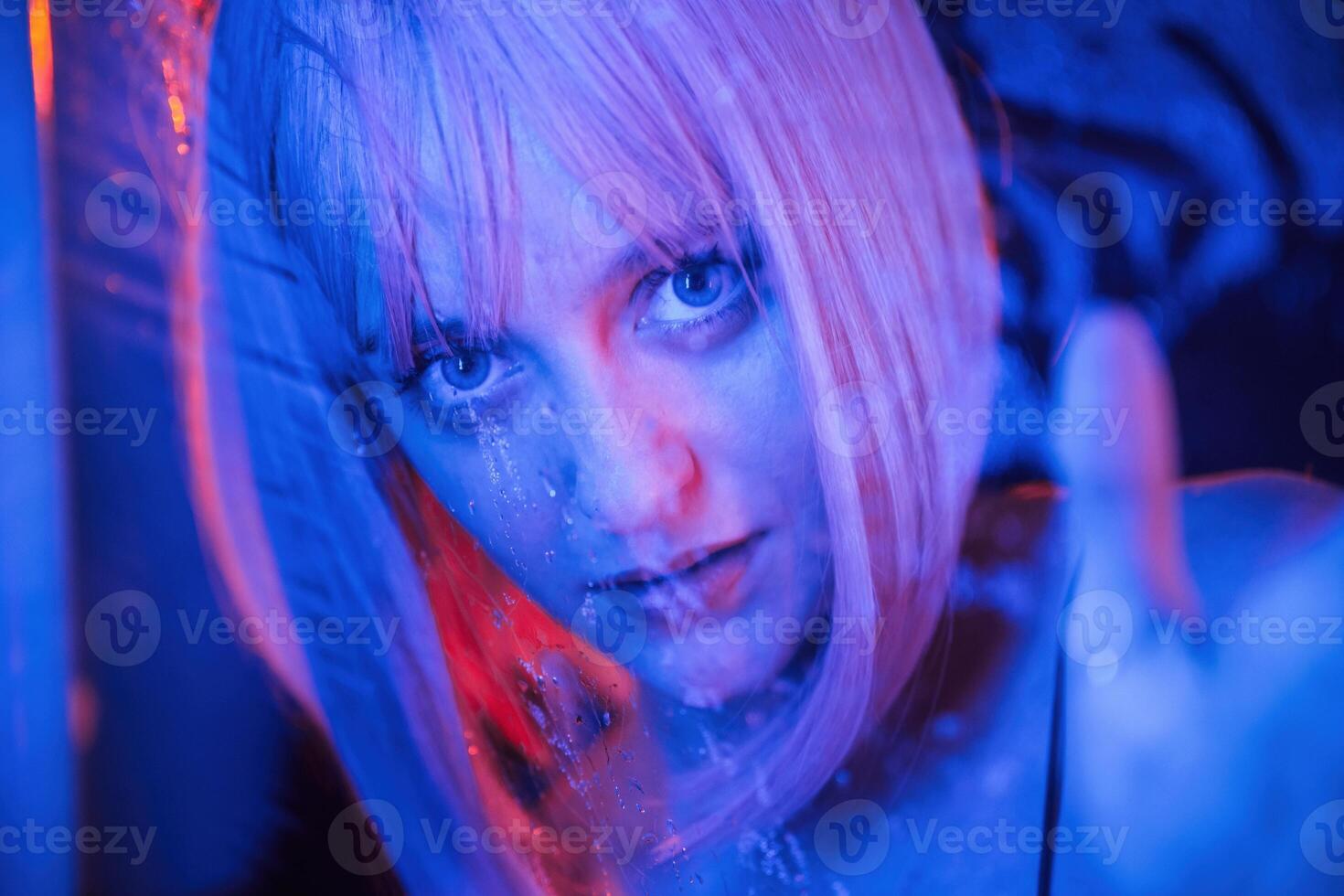 Blue color ,in the front and red is behind. Stylish woman with white hair is behind wet transparent plastic sheet photo