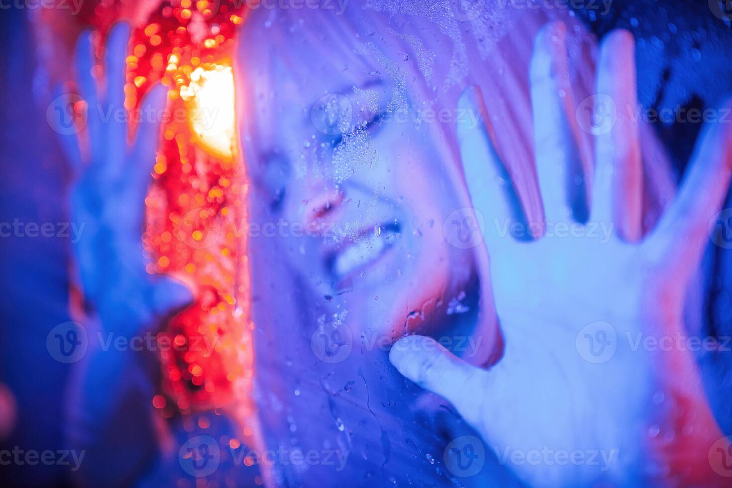 Hands, are on the surface. Stylish woman with white hair is behind wet transparent plastic sheet photo