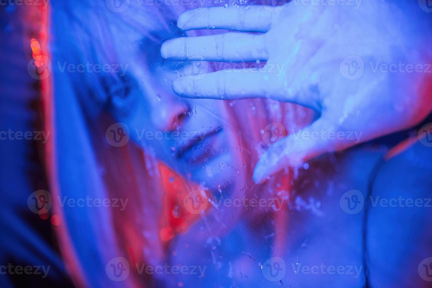 Blue ,color in the front and red is behind. Stylish woman with white hair is behind wet transparent plastic sheet photo