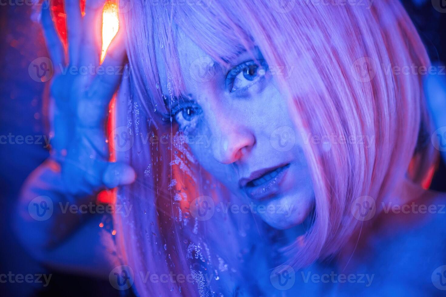 Blue, color in the front and red is behind. Stylish woman with white hair is behind wet transparent plastic sheet photo
