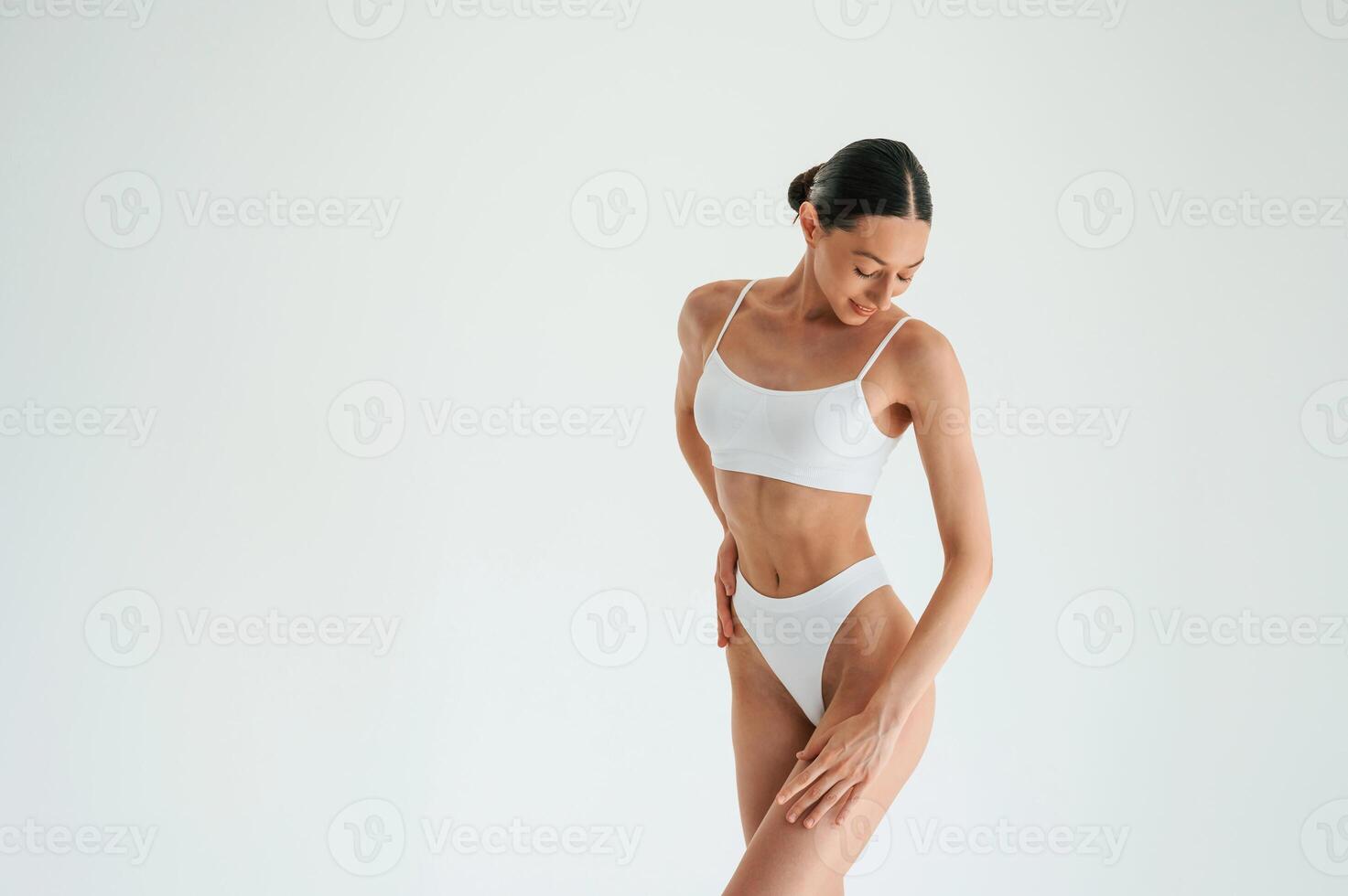 Standing and, posing... Woman in white underwear with slim body type against white background photo